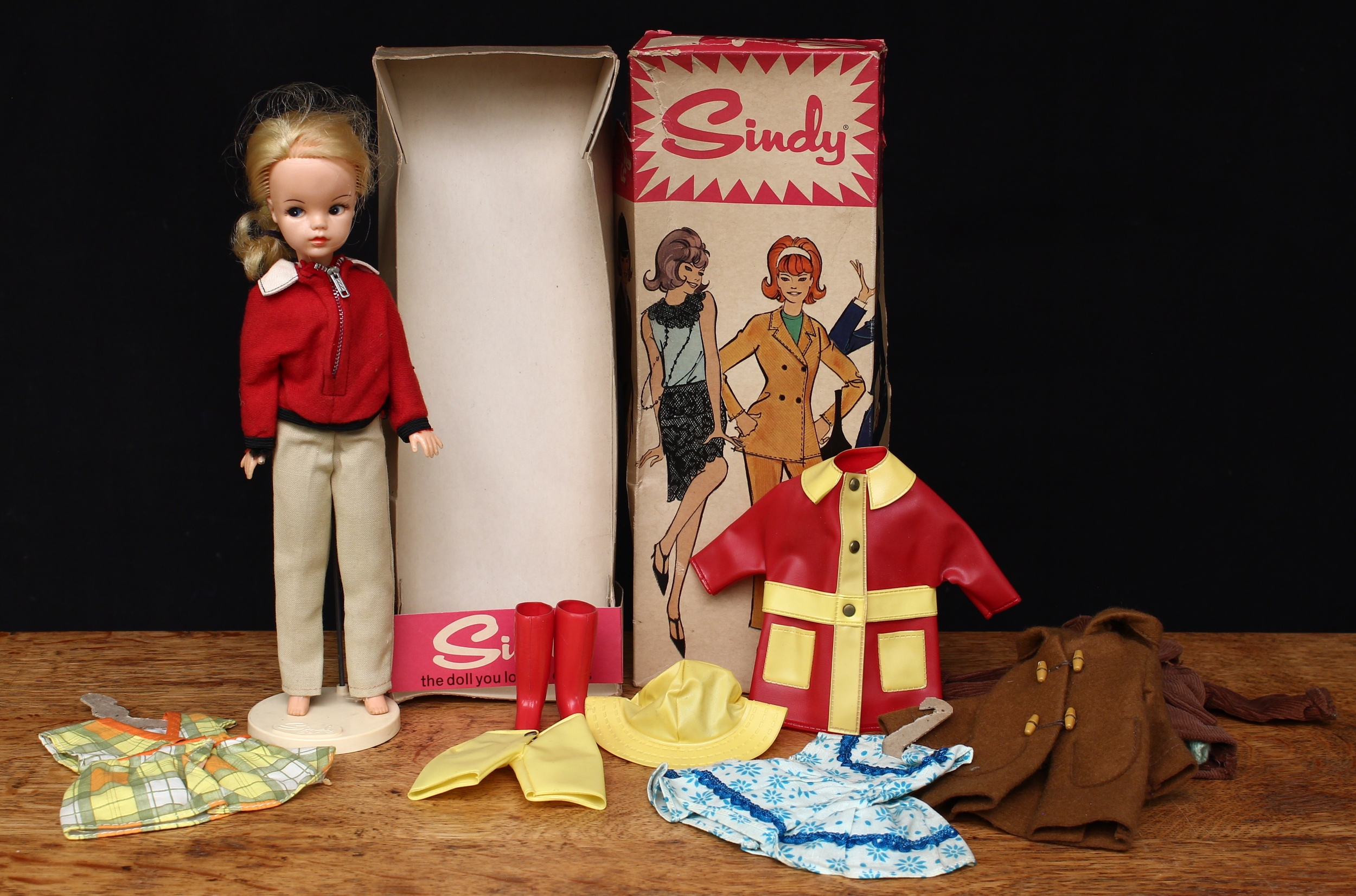 A late 1960's Pedigree 12GSS3 Sindy doll, blonde hair, side glancing blue eyes, wearing a red jacket with beige trousers, boxed with Sindy set stand; a collection Sindy clothing and accessories including the Sindy 'Rainy Day' outfit etc (quantity)