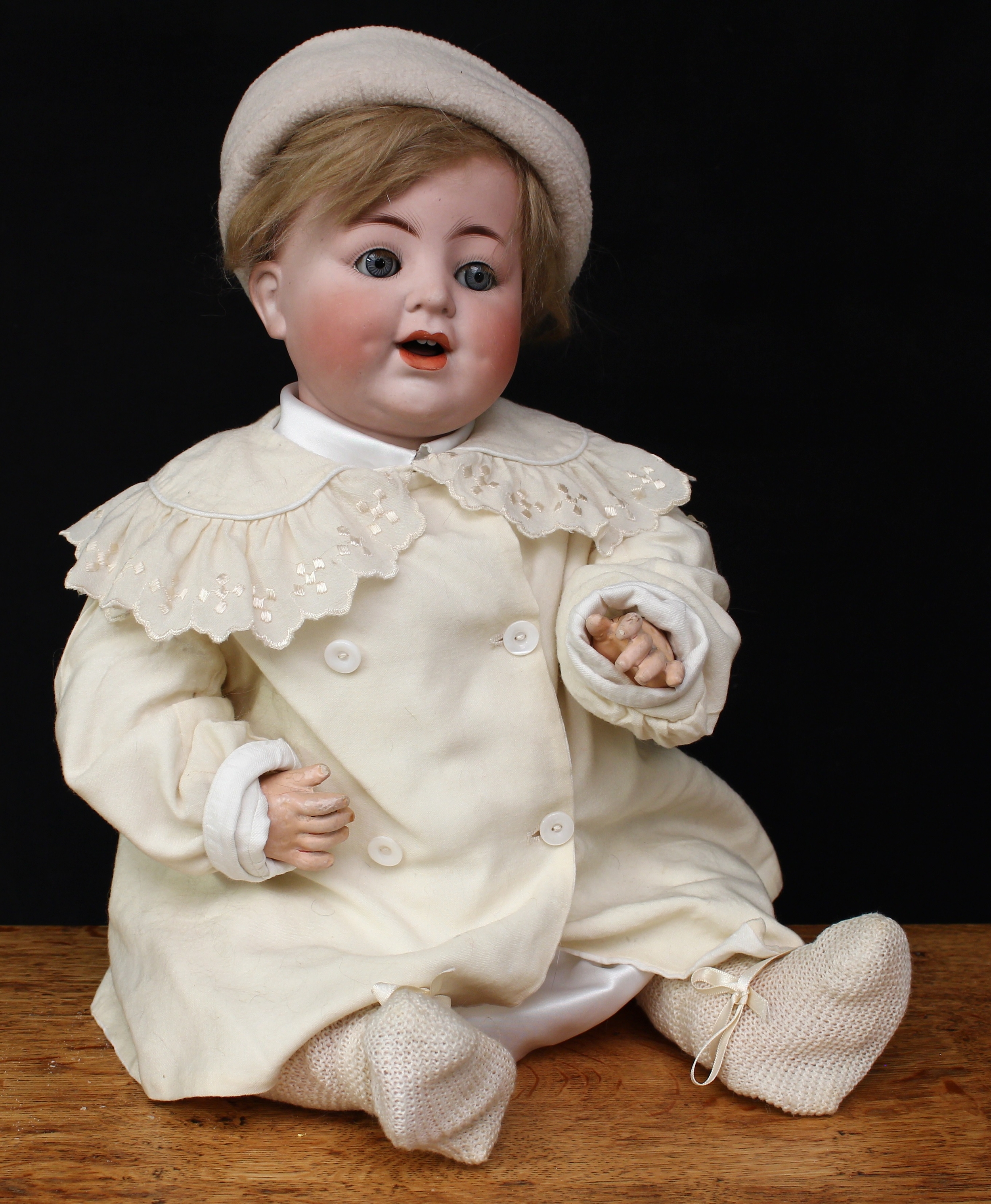 An Alt Beck & Gottschalck (Germany) bisque head and composition bodied doll, weighted sleeping blue glass eyes, painted features including fine eyelashes and brown feathered eyebrows, open mouth revealing teeth, blonde wig on a cardboard pate, impressed marks ‘ABG 1352 55 MADE IN GERMANY’, 55cm high