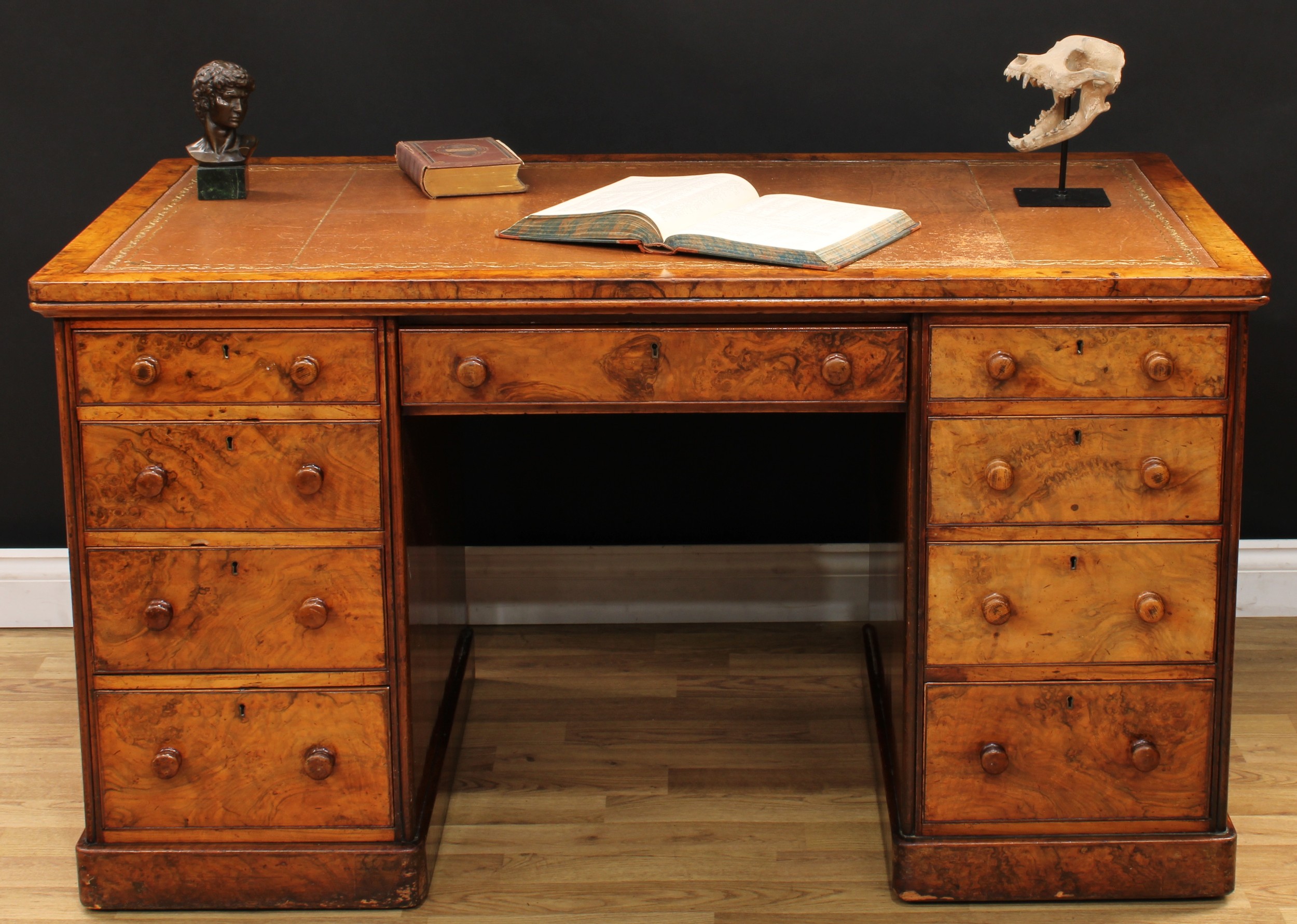 A Victorian burr walnut partner's desk, rounded rectangular top with inset tooled and gilt leather writing surface, above three frieze drawers, three further graduated drawers to each pedestal, a central frieze drawer and cupboards to verso, plinth base, the locks stamped H&C, By Royal Letters Patent, 75cm high, 138cm wide, 75cm deep, c.1880