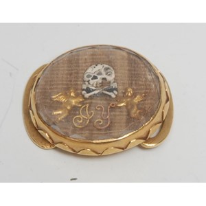 A late 17th/early 18th century gold coloured metal, rock crystal and plaited hair oval momento mori mourning slide, decorated with skull-and-crossbones and initials GY, 2cm wide, c.1700, 6g gross