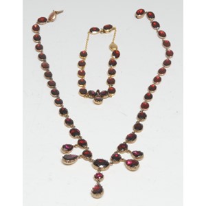 An Almandine garnet fringe necklace and bracelet suite,  composed of thirty five oval graduated almandine inset sections suspending five pear drop beads, mounted within an unmarked gold coloured metal frame, 40cm long;  similar seventeen stone bracelet, 17.5cm long, 30.8g gross