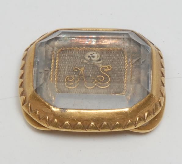 A late 17th/early 18th century gold coloured metal,  rock crystal and plaited hair canted rectangular momento mori mourning slide, decorated with skull-and-crossbones and initials AS, 2cm wide, c.1700, 8g gross