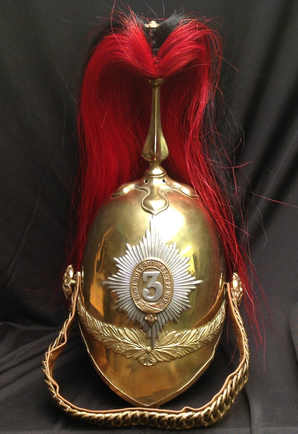 British Victorian 1871 Pattern Cavalry  Helmet. Brass skull with 3rd Dragoon Guards regimental helmet plate to front. Helmet has brass cross base and fluted plume holder which houses a falling red/black horse hair plume. Gilt metal rosette to top of holder. Brass rosettes which hold a replacement chin chain backed with brown imitation leather. No liner, only leather liner band present. Some unit stamps to rear rim of helmet which have been struck out "7 DG" "6720" "I.09" and an unstruck "1 DG 5386".
