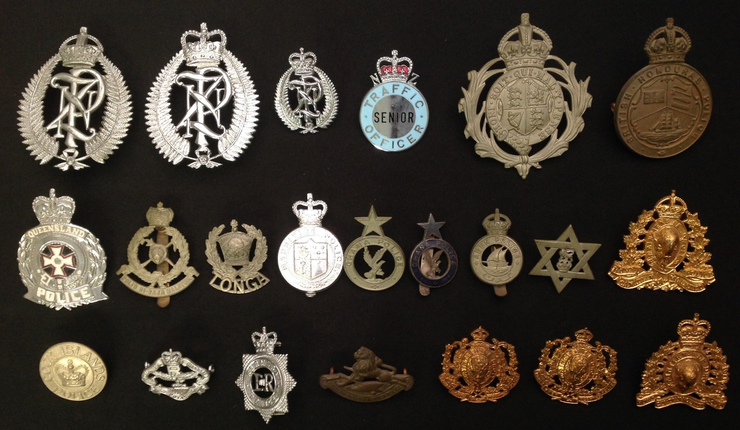 British Empire and Commonwealth Police badge collection comprising of: New Zealand Police in both Kings Crown and Queens Crown: Small Queens Crown NZ: Queens Crown enamelled NZ Senior Trafic Officer: Queensland Police in enamel: Queens Crown Cook Islands Police: Tonga Police: Kings Crown Aden Police: Ghana Police x 2: Queens Crown Bermuda: Queens Crown Mauritius: Kings Crown British Honduras: Malaysia: British South Africa Police: Northern Rhodesia Police: Kings Crown North West Mounted Police x 2: King and Queens Crown RCMP: West Indies, Trinidad & Tobago  Police Kings Crown Cap Badge, etc. (22)