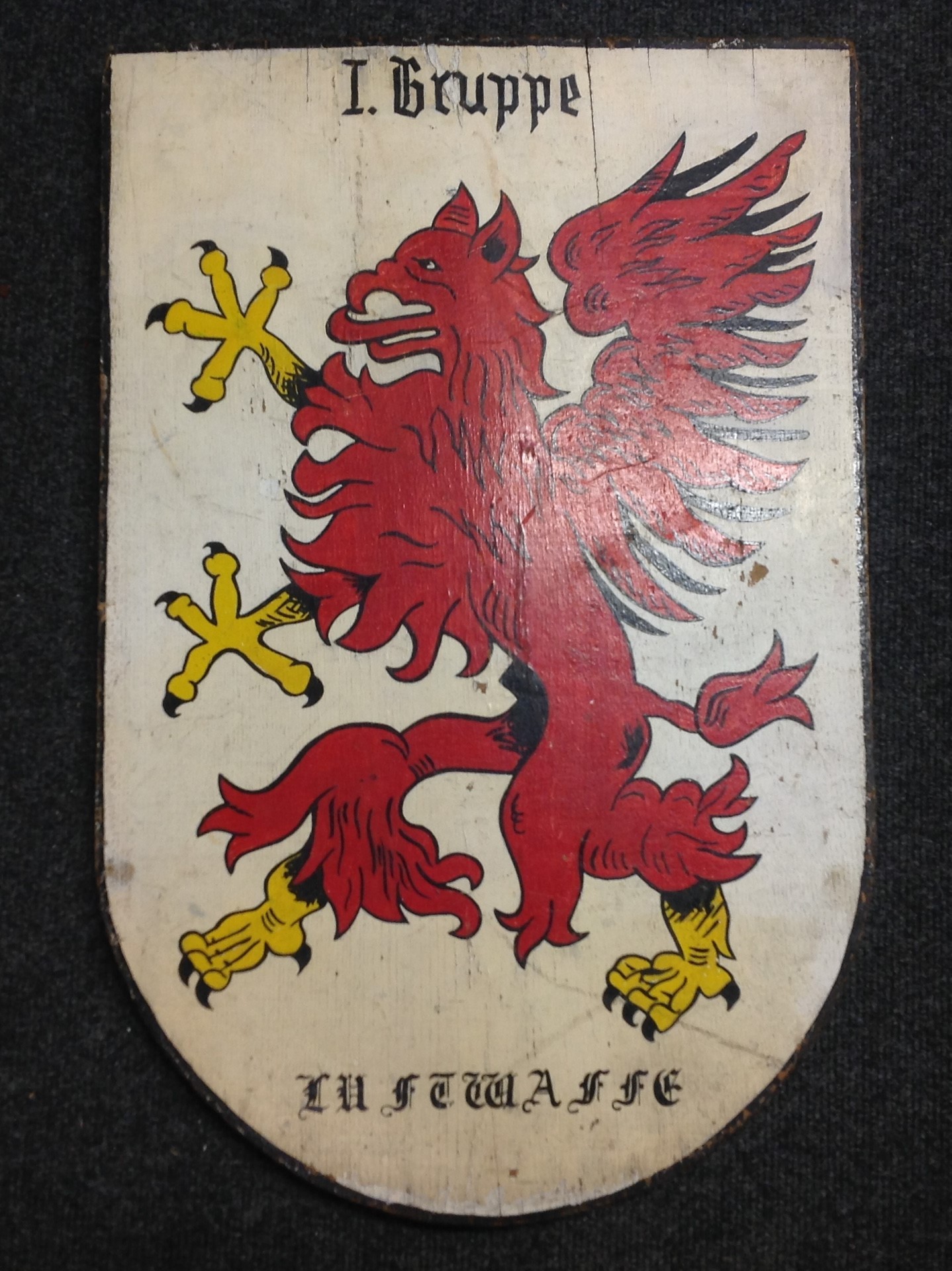 WW2 Third Reich Luftwaffe Hand Painted Plaque with the insignia of I Gruppe, Lehrgeschwader 1. Size 605mm x 397mm. Reverse has handwitten penciled inscription "4 G 1" along with "Uffz Stuchli K mitnehmen". Wood is 20mm thick. Two screws to which a length of electrical wire is attached for hanging. Weight 3.6kgs.