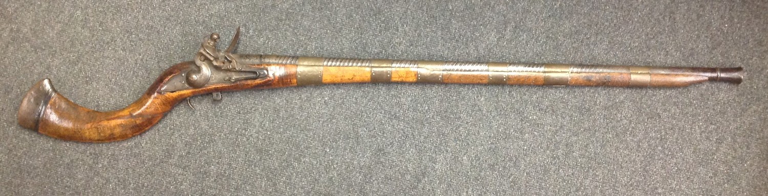 Indian Flintlock Musket with 835mm long smooth bore twisted steel barrel. Working action. Lock is East India Company marked along with 1816. Traditional Indian style stock. Broad brass barrel bands. Overall length 1170mm. Section 58, no licence required.