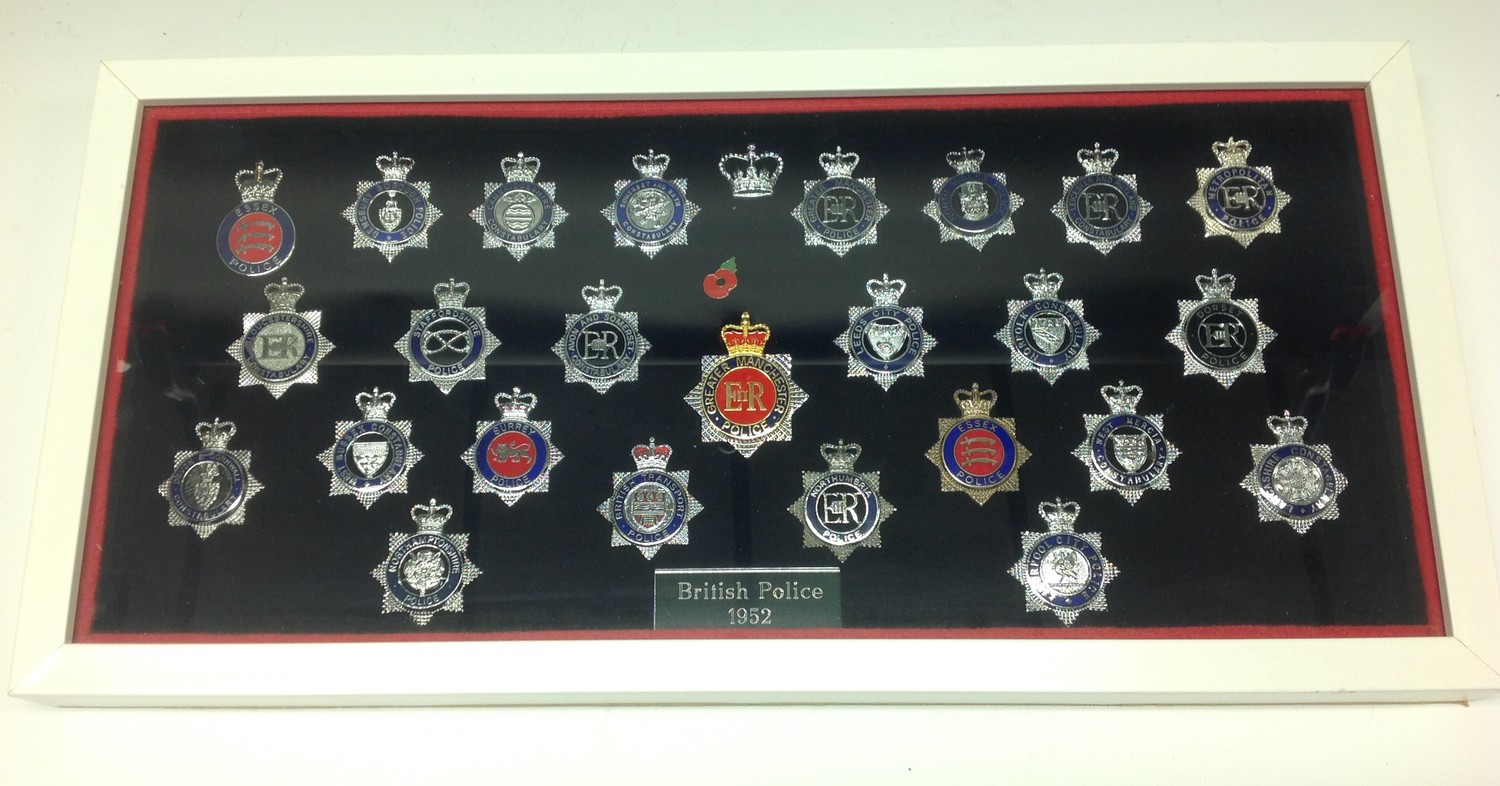 A collection of framed British Police cap badges entitled "British Police 1952". 25 ERII Queens crown badges in total to include: Greater Manchester x 2, Essex, Dewbury Borough, Cambridgeshire, Somerset and Bath, North wales, Lecicester & Rutland, Metropolitan, Gloucestershire, Staffordshire, Avon & Somerset, Leeds City, Norfolk Constabulary, Dorset, Devon & Cornwall, West Sussex, Surrey, British Transport Police, Nothumbria, Essex, West Mercia Constabulary, Lancashire Constabulary, Northamptonshire, and Liverpool City Police. Overall frame size 525mm x 255mm.