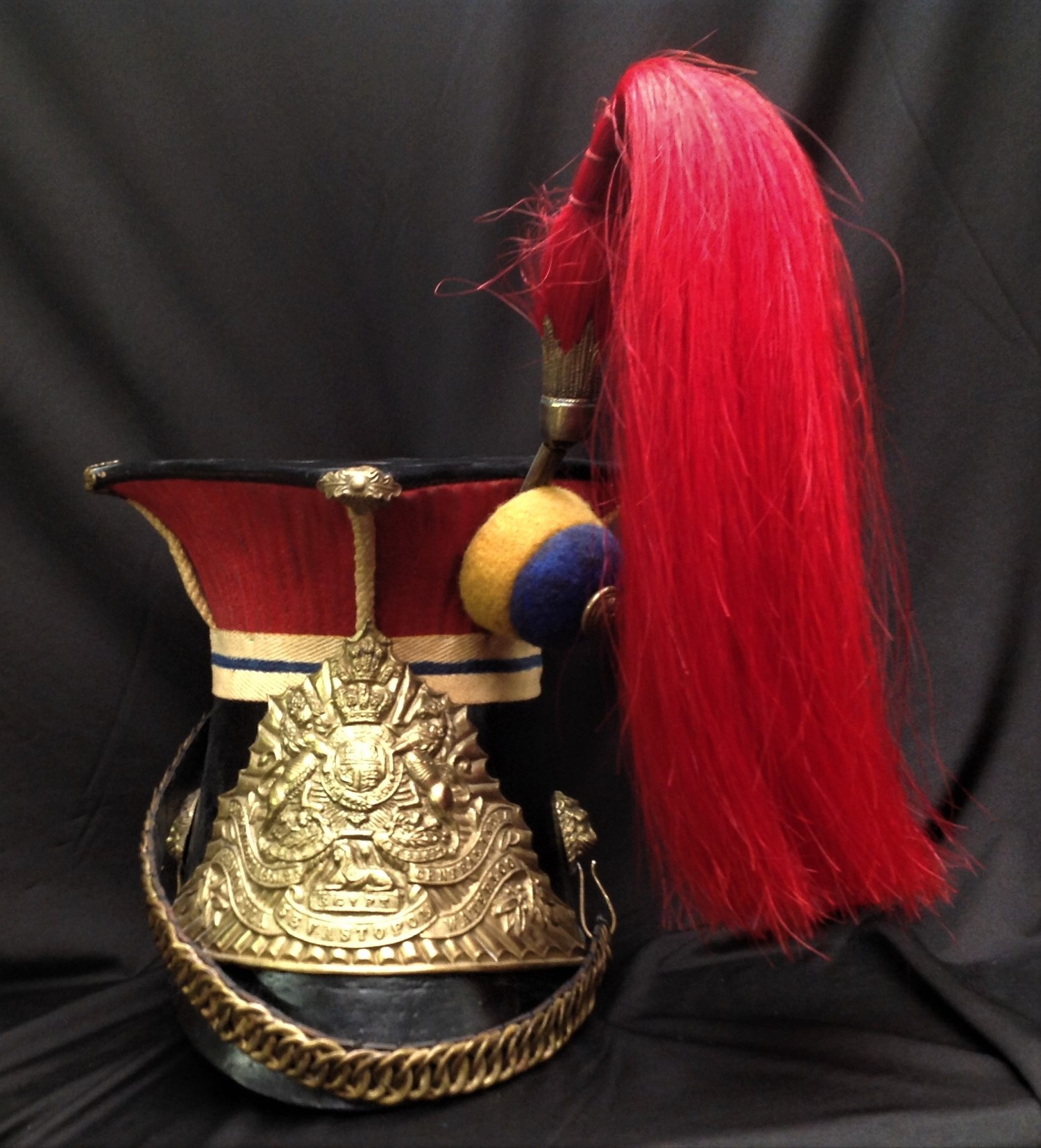 Reproduction dating from the late 20th Century of a Victorian 12th Lancers Shako Cap. Plume socket with red enlisted man's horse hair plume for the Prince of Wales's Royal Lancers. Helmet plate with Queens Crown and battle honours. Black leather backed chin chain. Lion's mask chin chain mounts. Black leather peak. Black leather sweatband. Size approx modern 57.