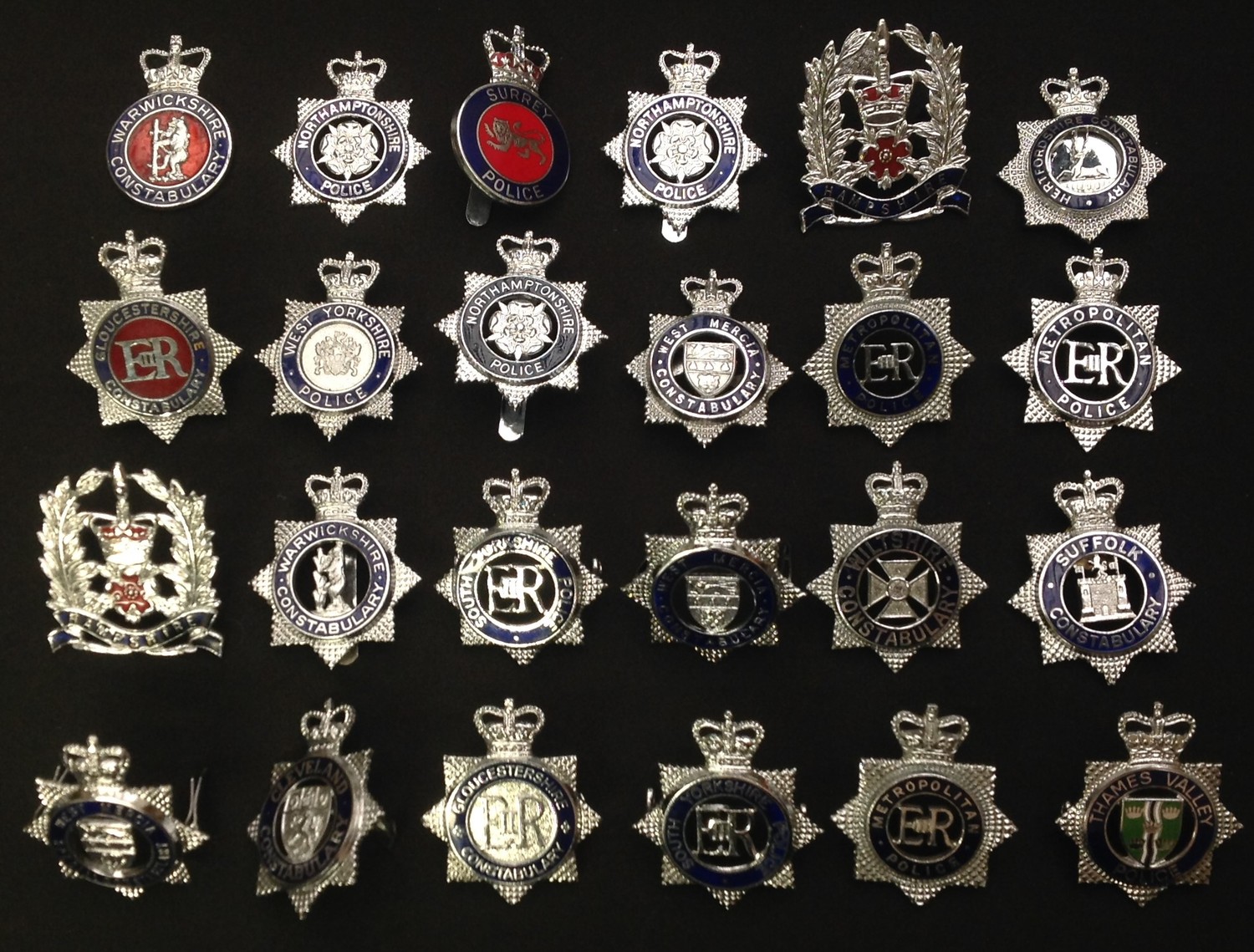 A collection of British Queens Crown Police cap badges all with coloured enamels to include: Metropolitan Police x 3, Northamptonshire Police x 3, West Mercia x 2, Gloucestershire  Constabulary x 2, Surrey Police, South Yorkshire x 2, Thames Valley, Suffolk Constabulary, West Mercia Special Constabulary, Warwickshire Constabulary, Hertfordshire Constabulary, Hampshire x 2, West Yorkshire, Cleveland, Wilts, etc. (24)
