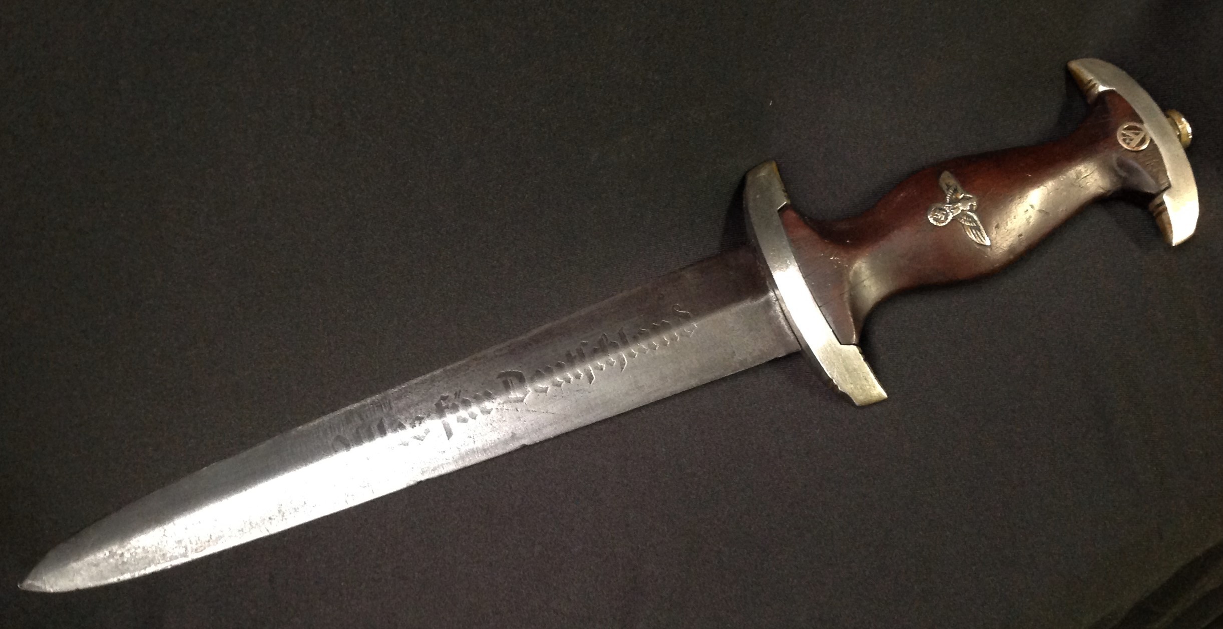 WW2 Third Reich SA Dienstdolch SA Dagger with 210mm long double edged blade with "Alles Fur Deutschland" motto and makers mark for "Herm. Konejung, Solingen". Crossguard is SA Gruppe marked "B" for Berlin-Brandenburg. Overall length 336mm. Guards are early nickle silver examples. Wooden grip with some chips and cracks but complete with eagle and SA insignias. No scabbard.