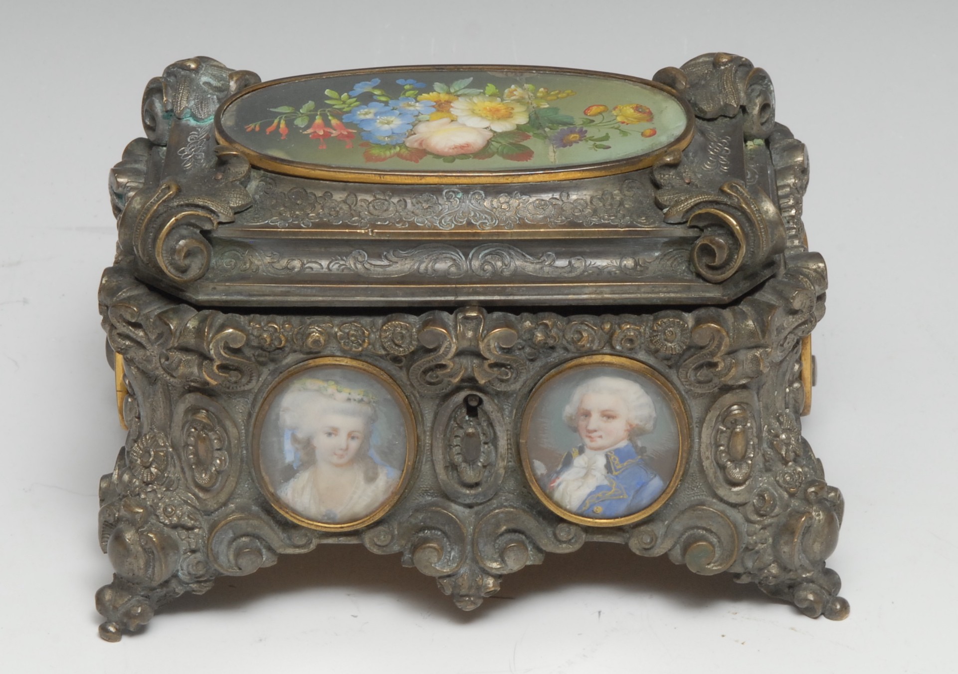 A 19th century French Rococo Revival silvered table casket, cast throughout with scrolls, flowers, and foliage, applied with portrait and still life miniatures, hinged cover, 15cm wide, c. 1870