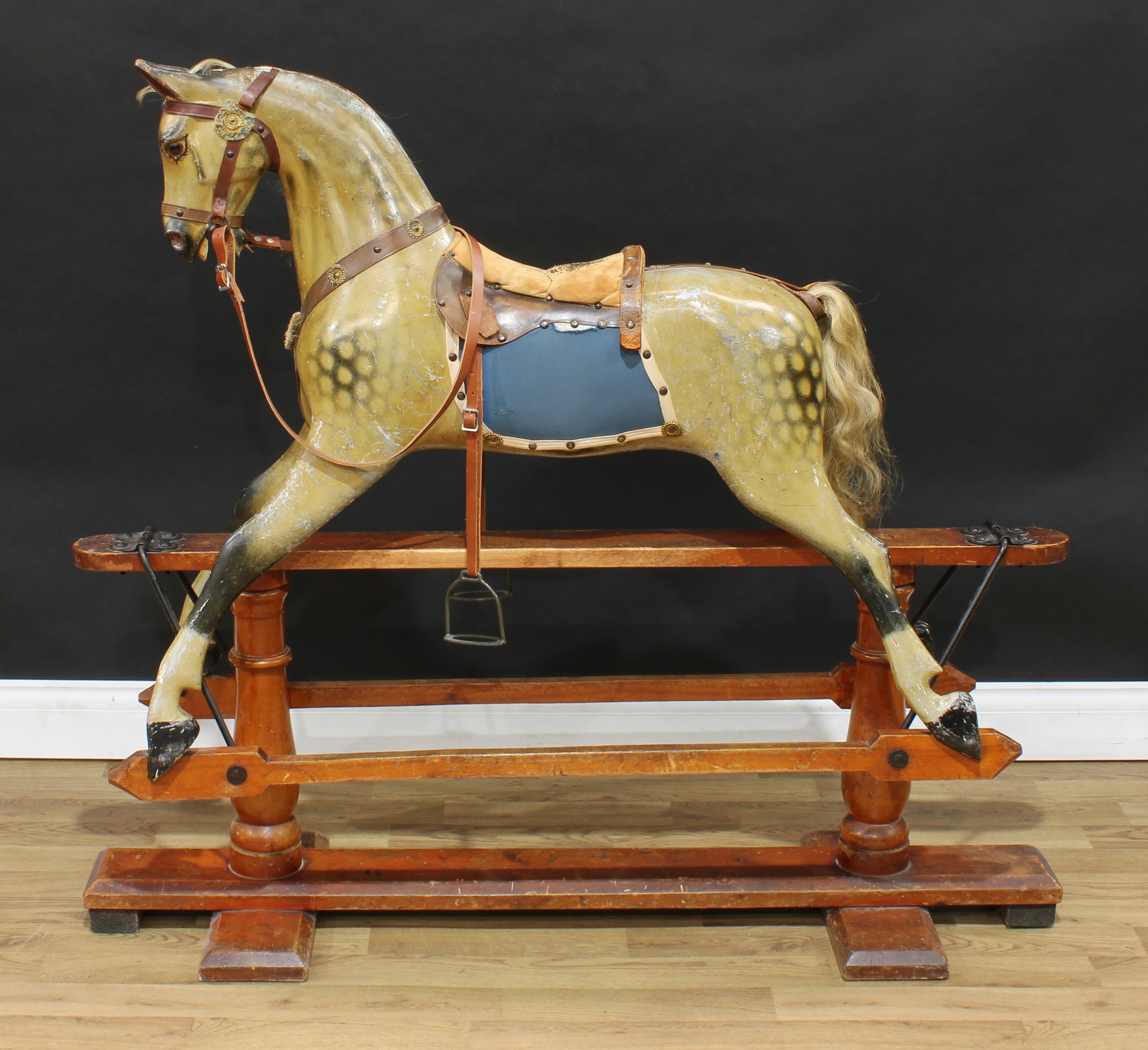 A late 19th/early 20th century English rocking horse on safety stand, probably by F H Ayres, the carved, gesso and painted dappled horse with pricked ears, flared nostrils and open mouth revealing teeth, real horse hair mane and tail, the body with outstretched legs on a safety stand stamped '6', 127cm long
