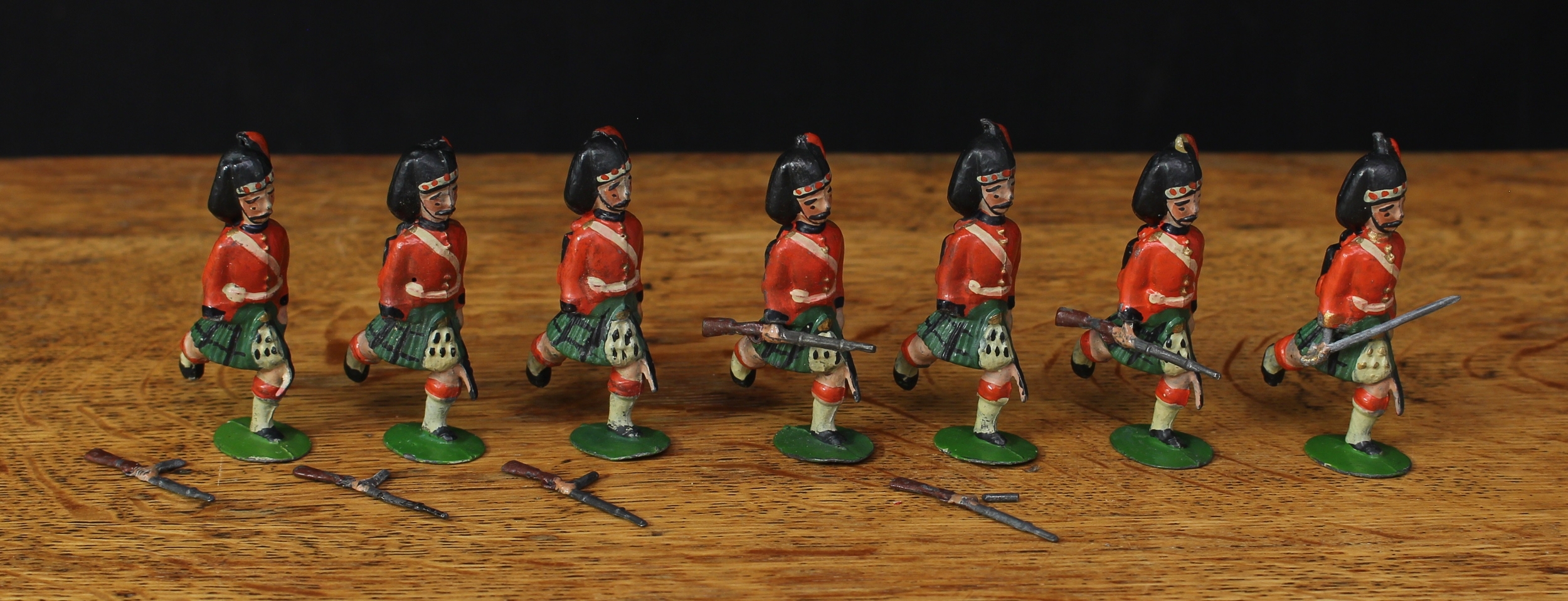 W Britain (Britains) No.11 The Black Watch, comprising an officer with sword and six Highlanders, each running with rifles at the trail, each with plug hands and unmarked oval bases, unboxed (7)