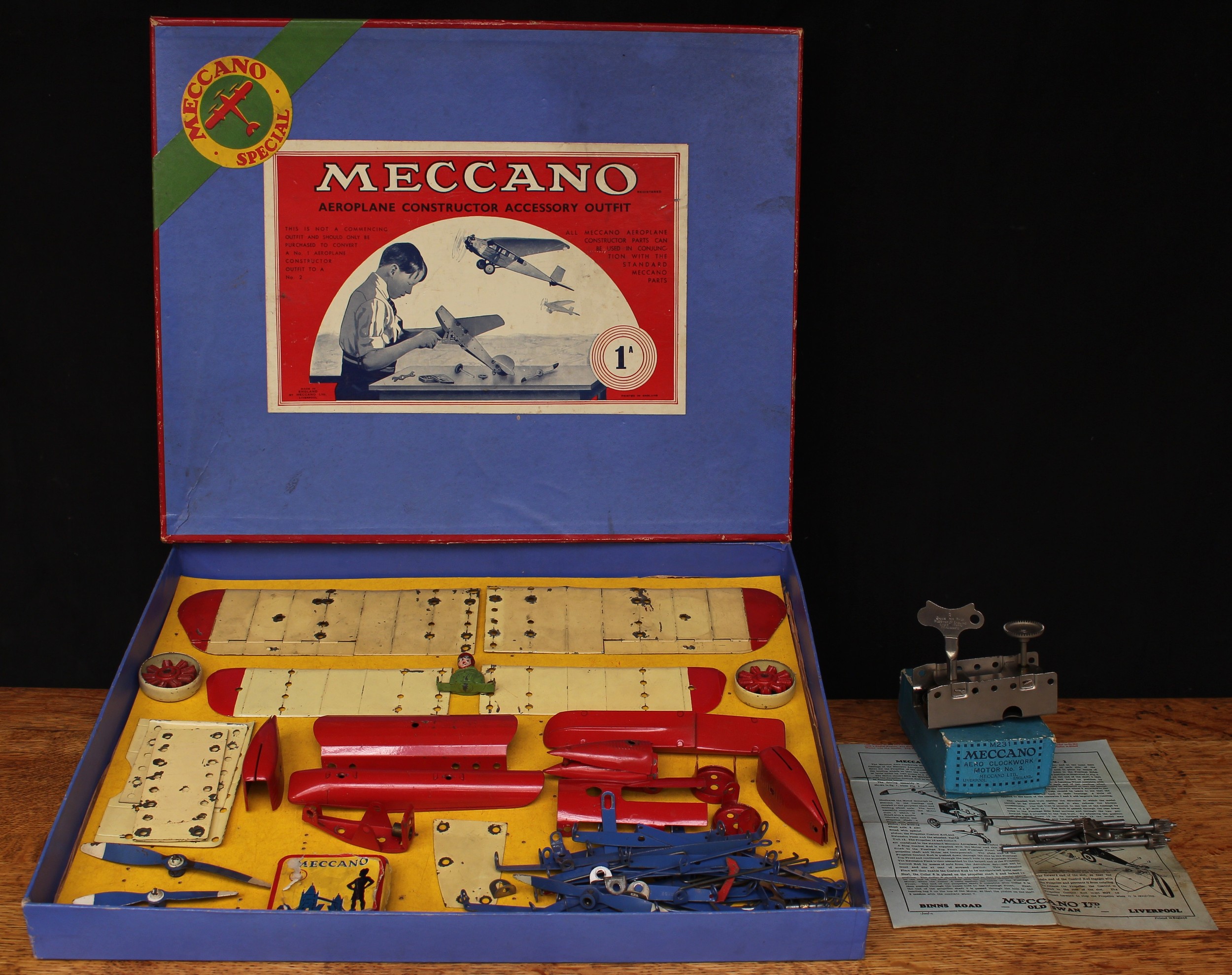 A 1930's Meccano No.1A Special aeroplane constructor accessory outfit, comprising various red, blue and cream outfit parts, unstrung from inner cardboard display piece; a Meccano M231 aero clockwork motor No.2, boxed with key and instructions sheet (2)