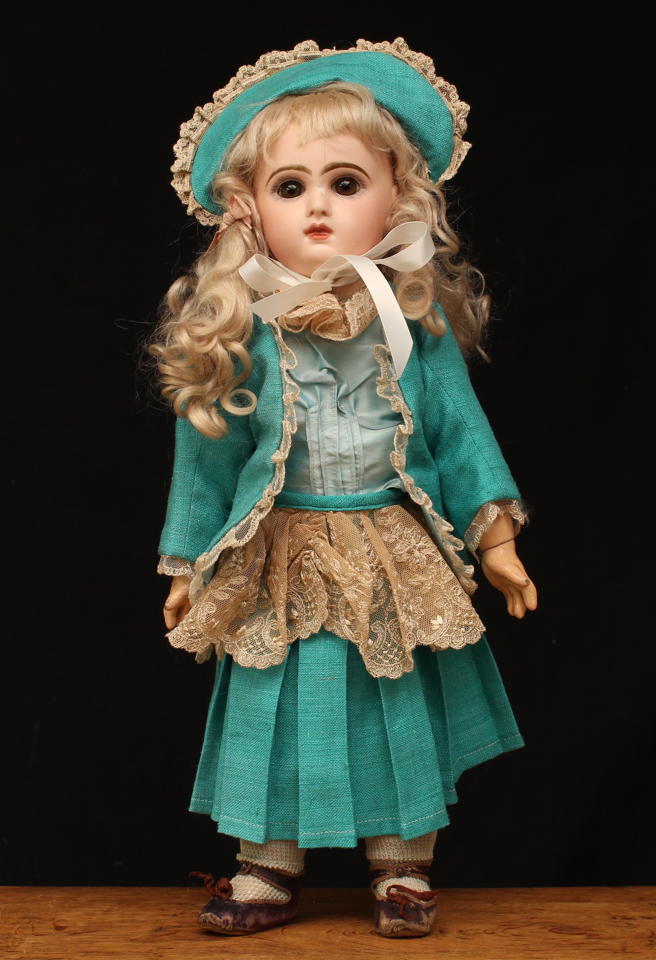 A Dèposè Tete Jumeau bisque head and painted composition Bèbè, size 7, inset fixed brown glass eyes, painted features including fine eyelashes, brown feathered eyebrows and red lips, pierced ears, blonde wig on a cork pate, red printed mark to back of head 'DEPOSE TETE JUMEAU BTE S.G.D.G. 7' and blue printed mark to lower back 'BEBE JUMEAU', wearing a green turquoise jacket and dress with lace edge, bonnet and brown kid leather shoes, 43cm high