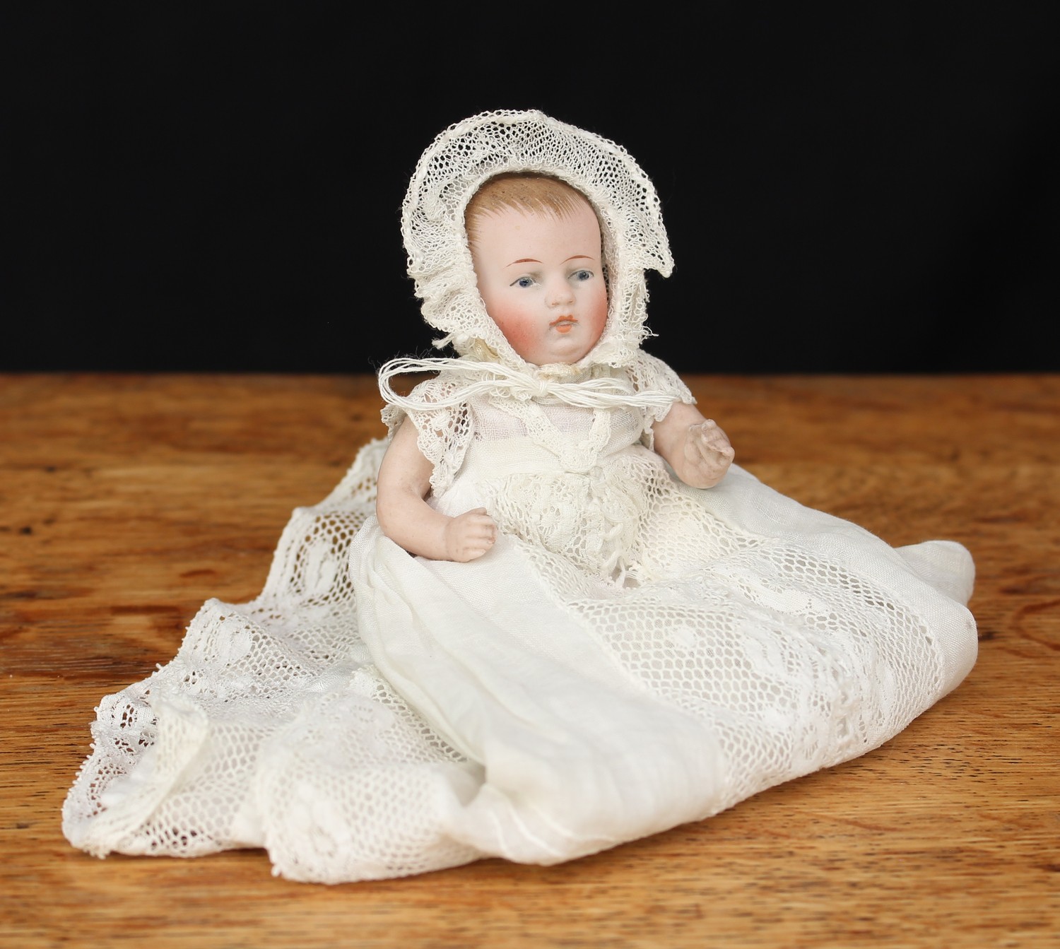 A German all bisque jointed miniature character baby doll, painted blue glass eyes and features including red lips and brown hair, impressed marks to upper back '830-1', wearing a white linen and lace gown with underclothes and bonnet, 10cm high, probably by JDK Kestner (Germany)