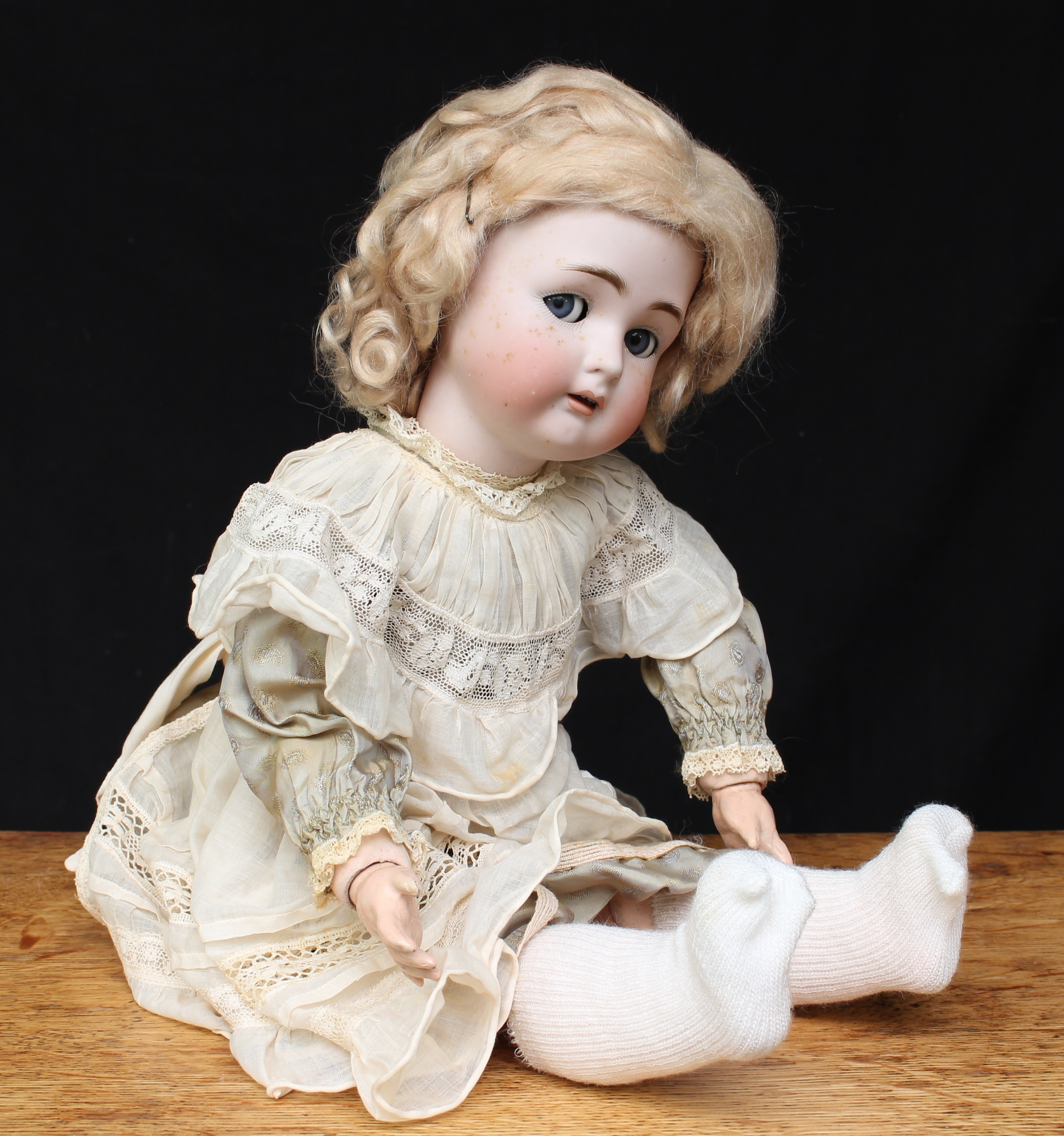 A Simon & Halbig/Kammer & Reinhardt (Germany) bisque head and ball jointed painted composition bodied doll, weighted sleeping and side glancing blue glass eyes, painted features including feathered eyebrows and fine eyelashes, open mouth revealing upper teeth, pierced ears, blonde wig, impressed marks 'SIMON & HALBIG K&R 55', wearing a white linen dress with underclothes, 52cm high