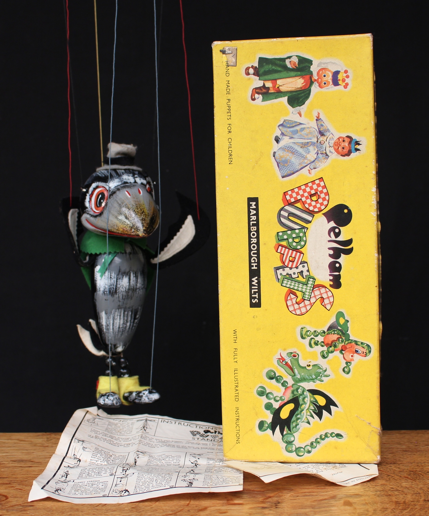 Pelham Puppets SL 63 Crow, from the SL 63 range, hollow moulded head with painted features, large orange eyes, felt wings and tail, beaded legs, wearing a green cape, label to verso of cape, boxed with instructions sheet