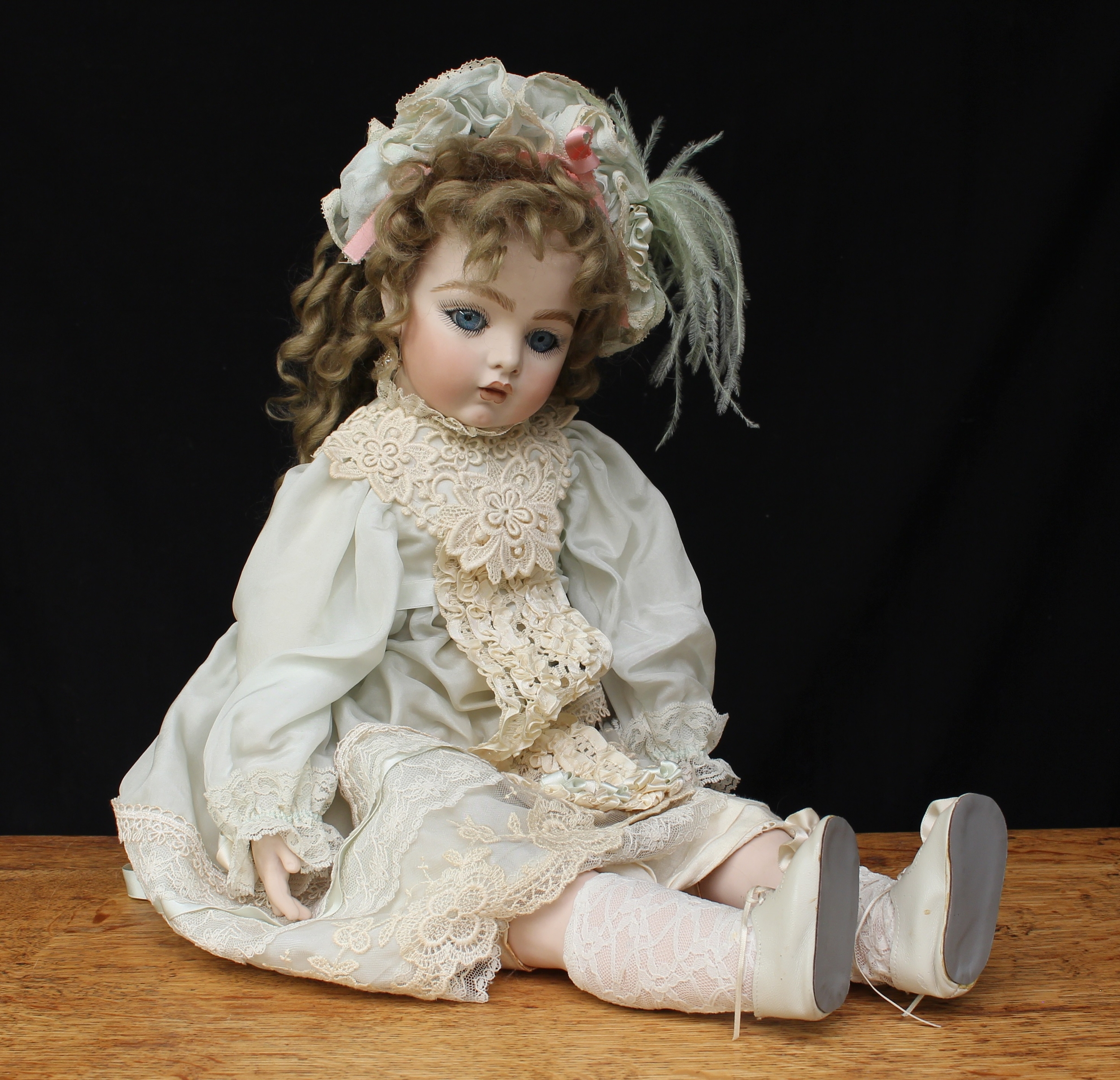A reproduction Bru bisque head and shoulder doll, partially stuffed cloth body with bisque arms and legs, inset fixed blue glass eyes, painted features including fine eyelashes and brown feathered eyebrows, pierced ears, blonde wig on a cardboard pate, various impressed marks, 65cm high