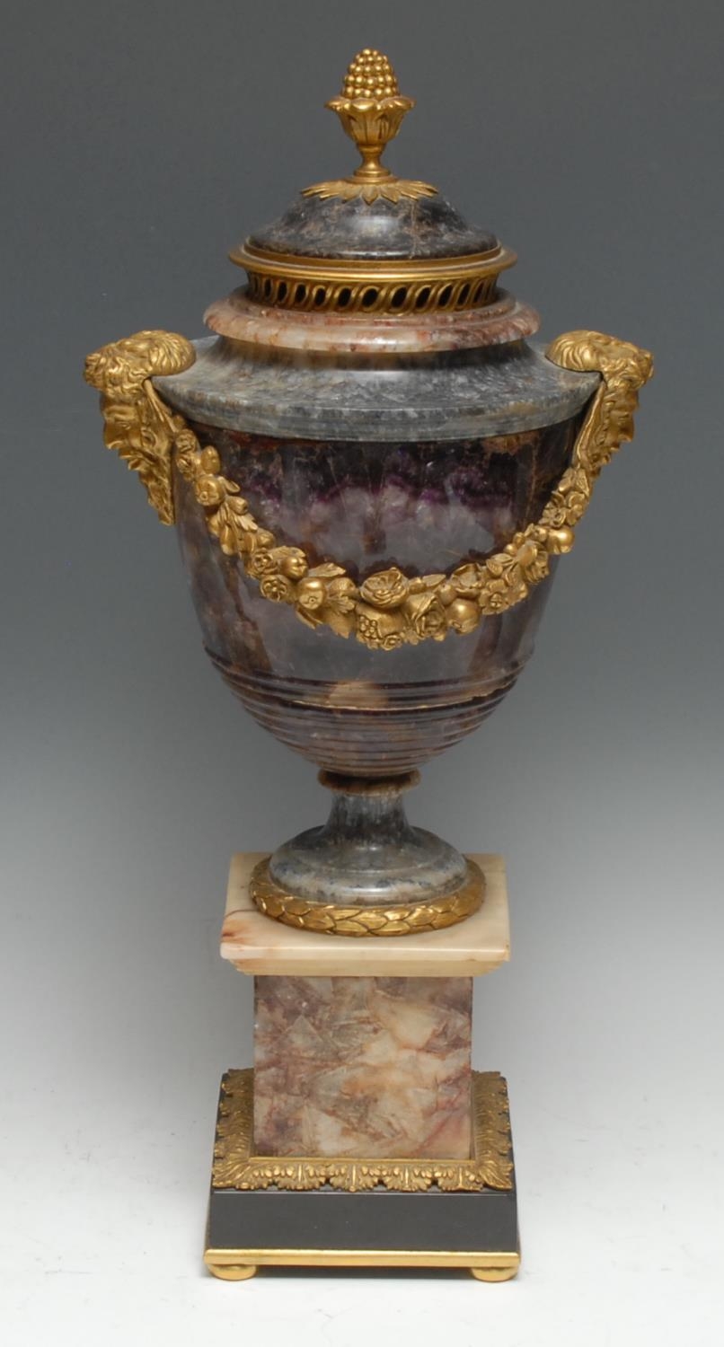 A 19th century ormolu mounted Derbyshire Blue John and fluorspar ovoid pedestal vase and cover, bud finial above a pierced frieze, cast and applied with masks and flowering swags, square pedestal base, bun feet, 46cm high