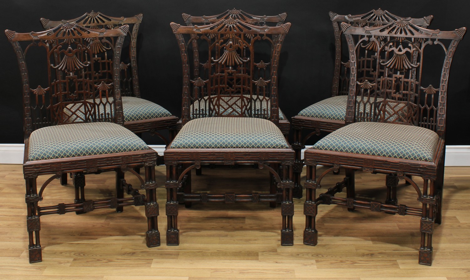 A set of six Chippendale Revival mahogany dining chairs, each with a cupid's bow cresting rail, the back shaped and pierced in the Chinese and cockpen taste, drop-in seat, blind fretwork apron, blocked cluster-columnar legs, twin-columnar stretchers, chamfered squamous square block feet, 94cm high, 58cm wide, the seat 45cm wide and 40cm deep, c.1900
