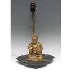 Chinese School (19th century), a gilt bronze, Boddhisatva, seated, holding a scroll, 16.5cm high, later mounted on a dark patinated bronze table lamp, as a lotus, 37.5cm high overall