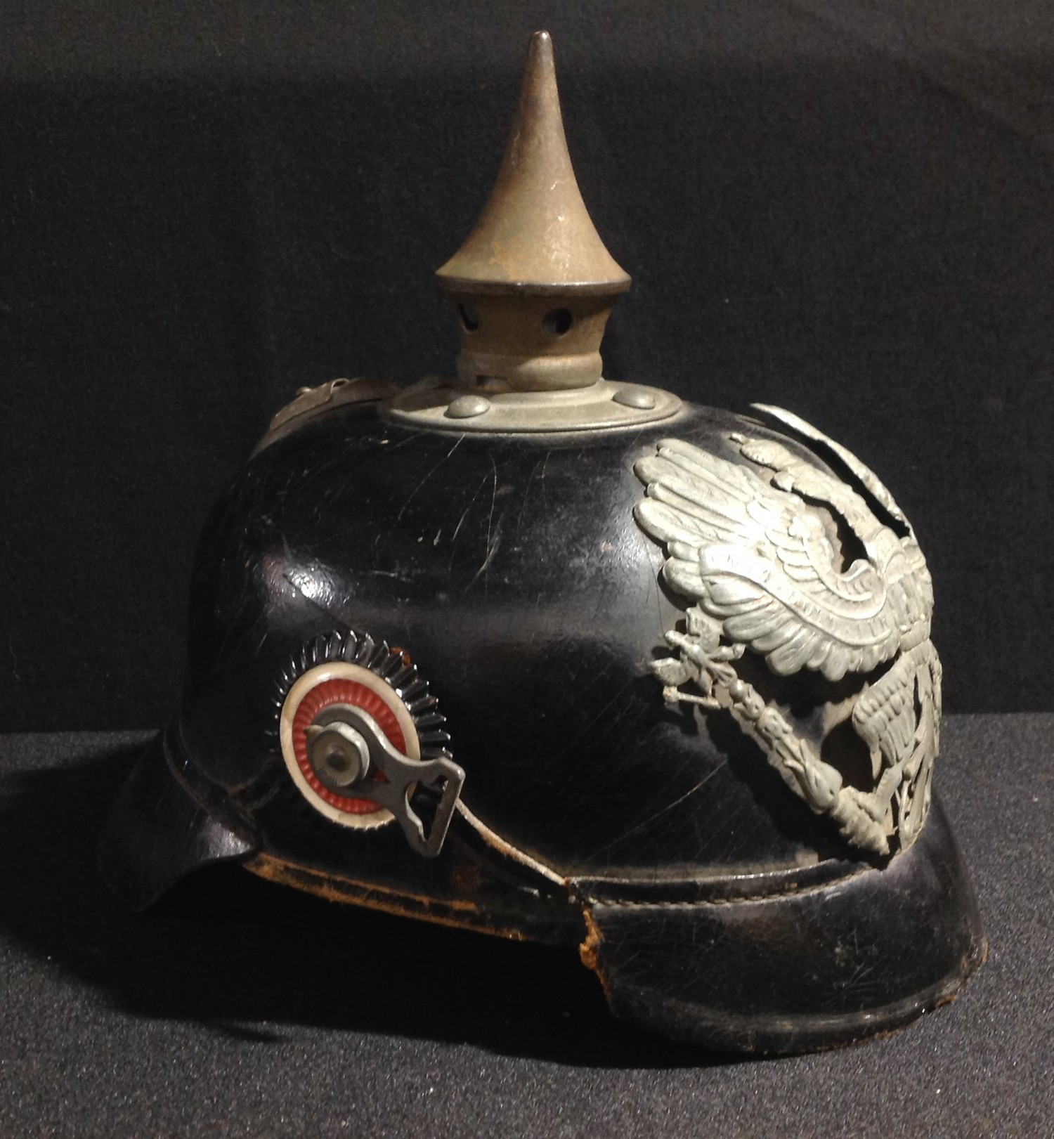 WW1 Imperial German Army Pickelhaube Helmet M1915. Complete with chinstrap fittings, but leather chinstrap is missing. Prussian helmet plate in wartime grey finish. Spike unscrews. Size marked "57". Maker marked "Gammersbach, Rolsdorf" and dated 1917. Nine finger leather liner present.