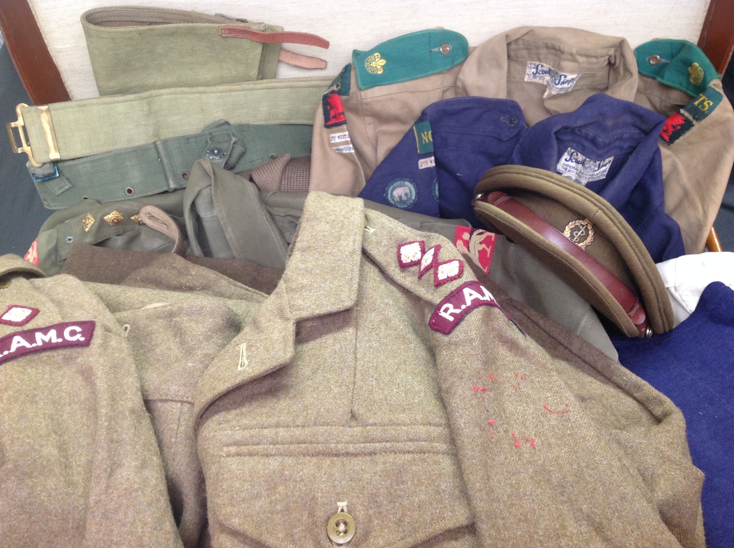 Post War British RAMC Officers uniform grouping to 453847 Captain J.A.K Wightman. This large and extensive collection of items to this officer is contained within a leather suitcase and comprises of: two 1949 pattern Battledress Blouses with RAMC insignia: Officers Service Dress cap with badge by Bates of London:  two pairs of 1949 pattern BD trousers: two Airtex Jungle Green shirts, one with full insignia: Jungle green shorts x 2: white dinner jacket: blue sports shorts x 2: CC41 marked blue swimming trunks: CC41 marked blue jumper: 1937 pattern web belt: 1944 pattern web belt: pair 1937 pattern gaiters: Officers tie: spare shirt collar: CC41 marked Blue Boy Scouts shirt with Notts insignia: khaki Boy Scout shirt with full Notts insignia: hose top socks in khaki and red: school scarf. Suitcase has pre 1948 LMS Railway luggage labels affixed.