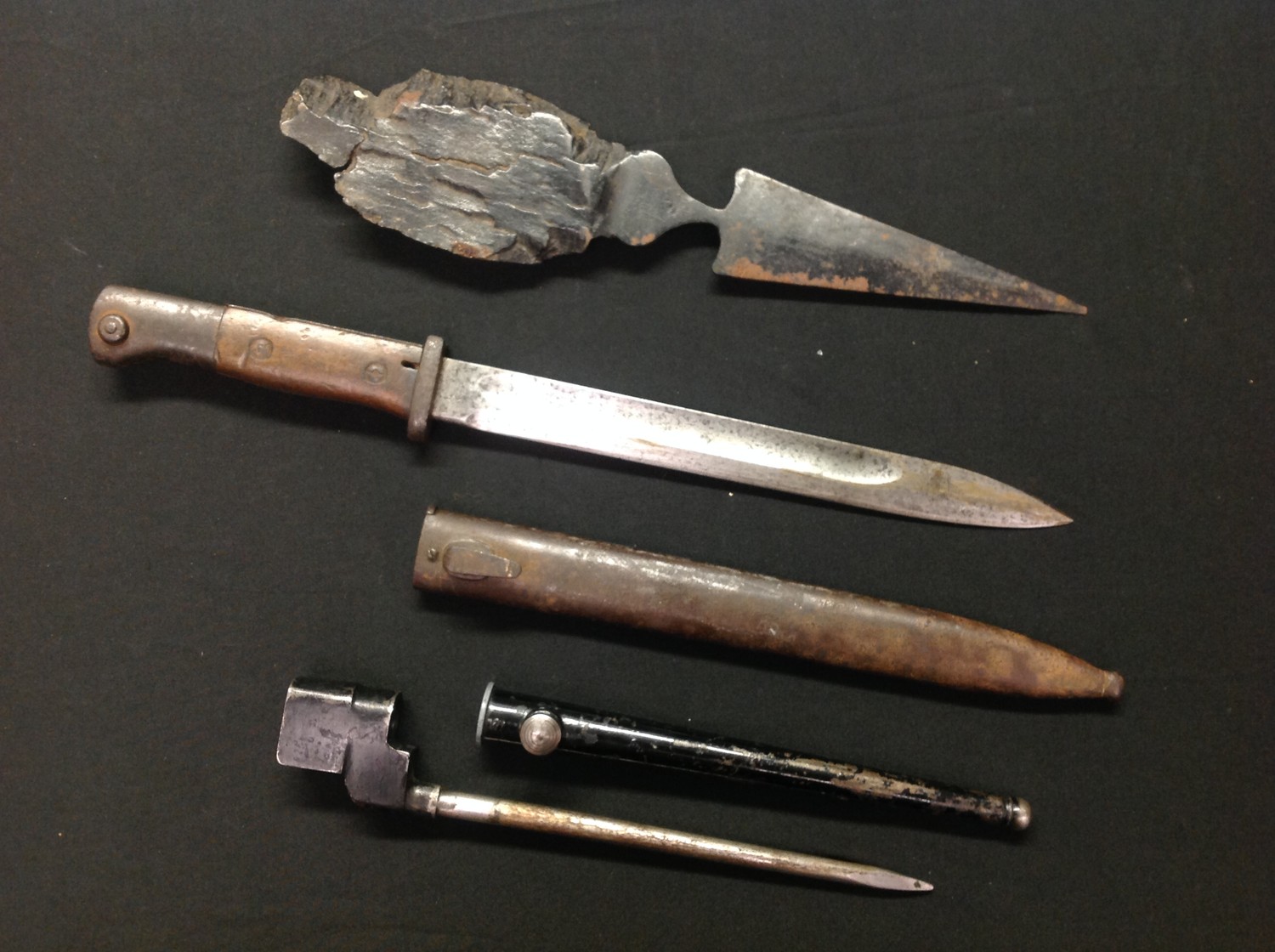 WW1 Imperial German Mauser G98 S1884/98 bayonet with single edged fullered 250mm long blade maker marked "Erfurt" plus "W15" to spine of blade. Guard is unit marked "15. U. 2. 12 ". Wooden grip with flash guard. Working release catch. Overall length 385mm. Complete with unit marked scabbard, 15. U. 89. Plus a large trench art shrapnel letter opener with 145mm spear point blade, overall length 320mm. Along with a WW2 British No4 Spike bayonet and scabbard. (3)