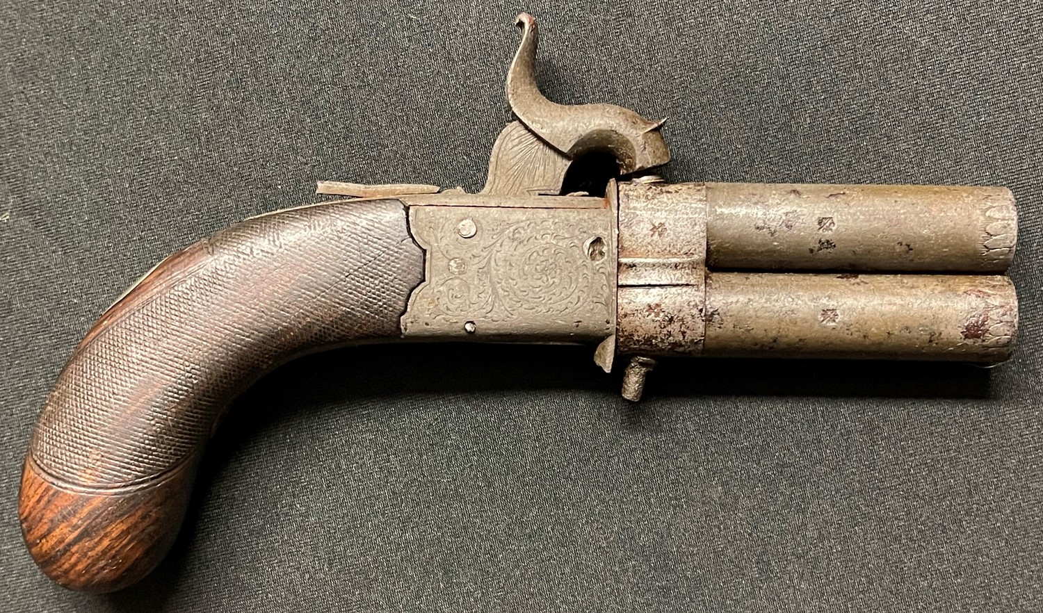 A small revolving double barrel Percussion cap pistol. Barrel length 67mm. Heavily rifled bore approx 8mm. British proof marks. Overall length 170mm. Folding trigger. Silver escutcheon plate which is plain. Action a/f. Section 58, no licence required.