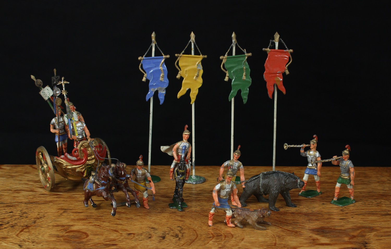 George Heyde (GH & Co Dresden, Germany) set of solid painted lead figures from the "Triumph of Germanicus" set, comprising of four Vexillium type banners, a Roman handler with bear, a Roman handler with wolfhound, two Roman soldiers on foot playing a long trumpet or bucina, a Roman cavalryman and an elegant chariot set with two horse team being led by a single footman and a driver accompanied by two standard bearers (10)