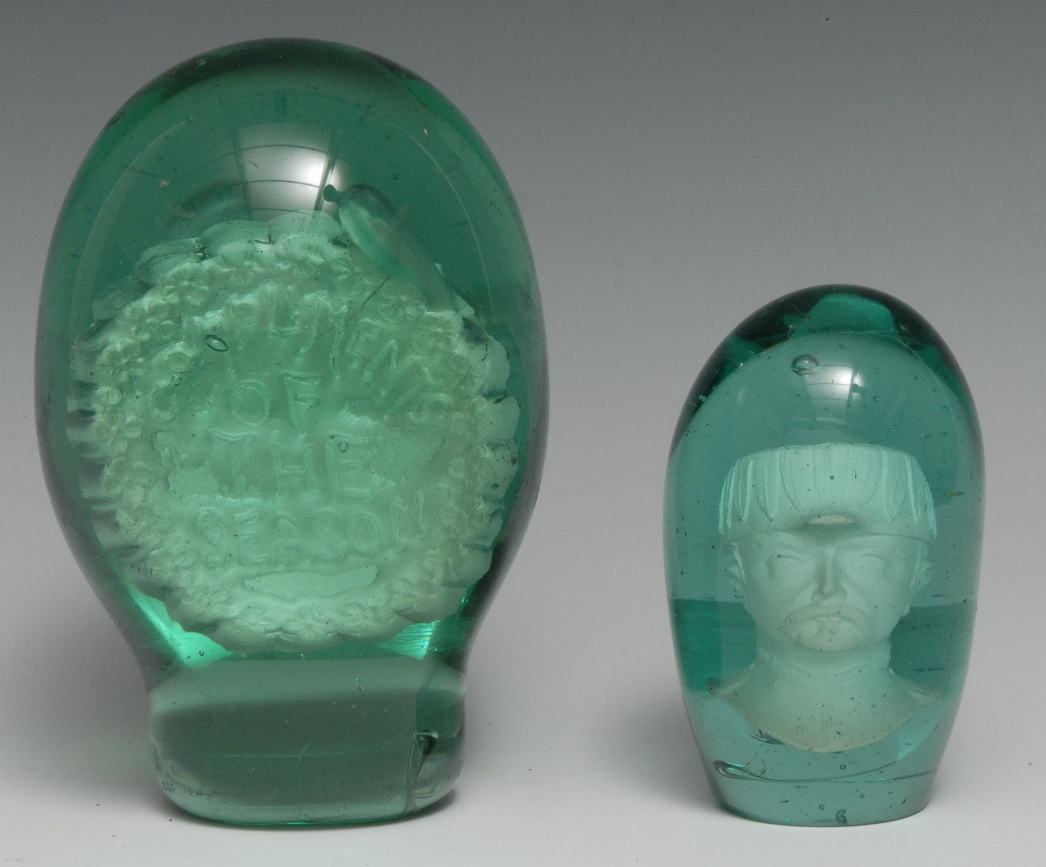 A Victorian green glass dump, sulphur inclusion inscribed Compliments of the Season, 15cm high, c. 1880; another dump paperweight, enclosing a military portrait, 10.5cm, c. 1880 [2]