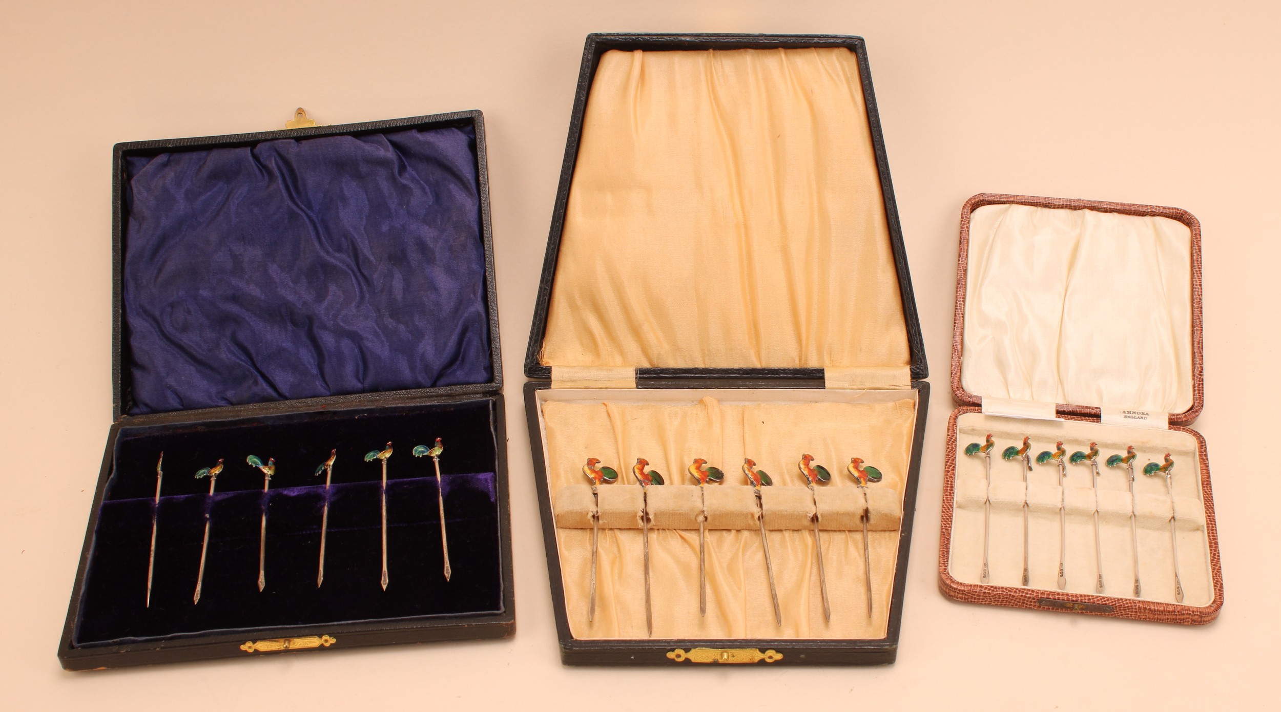 A set of six George V silver Art Deco cocktail sticks, each enamelled terminal as a cockerel, 8.5cm, Birmingham 1927, boxed; another set, marked "silver", cased; another set of six silver cocktail sticks, enamel cockerel terminals, Birmingham 1930, cased (3)