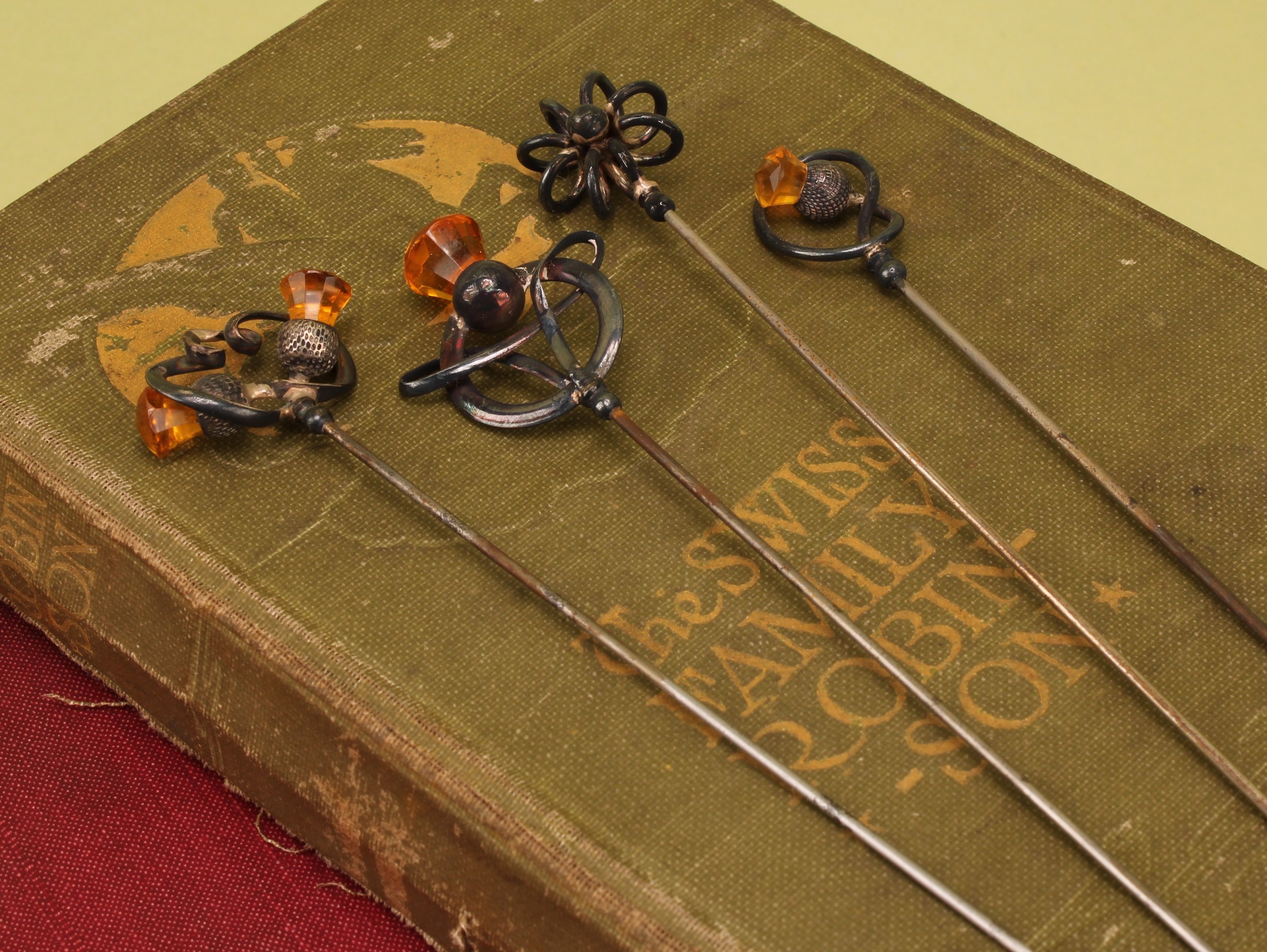 Charles Horner - an Art Nouveau silver thistle topped hat pin, set with orange paste stone, 16cm long, Chester 1912; other Charles Horner silver topped hat pins (4)