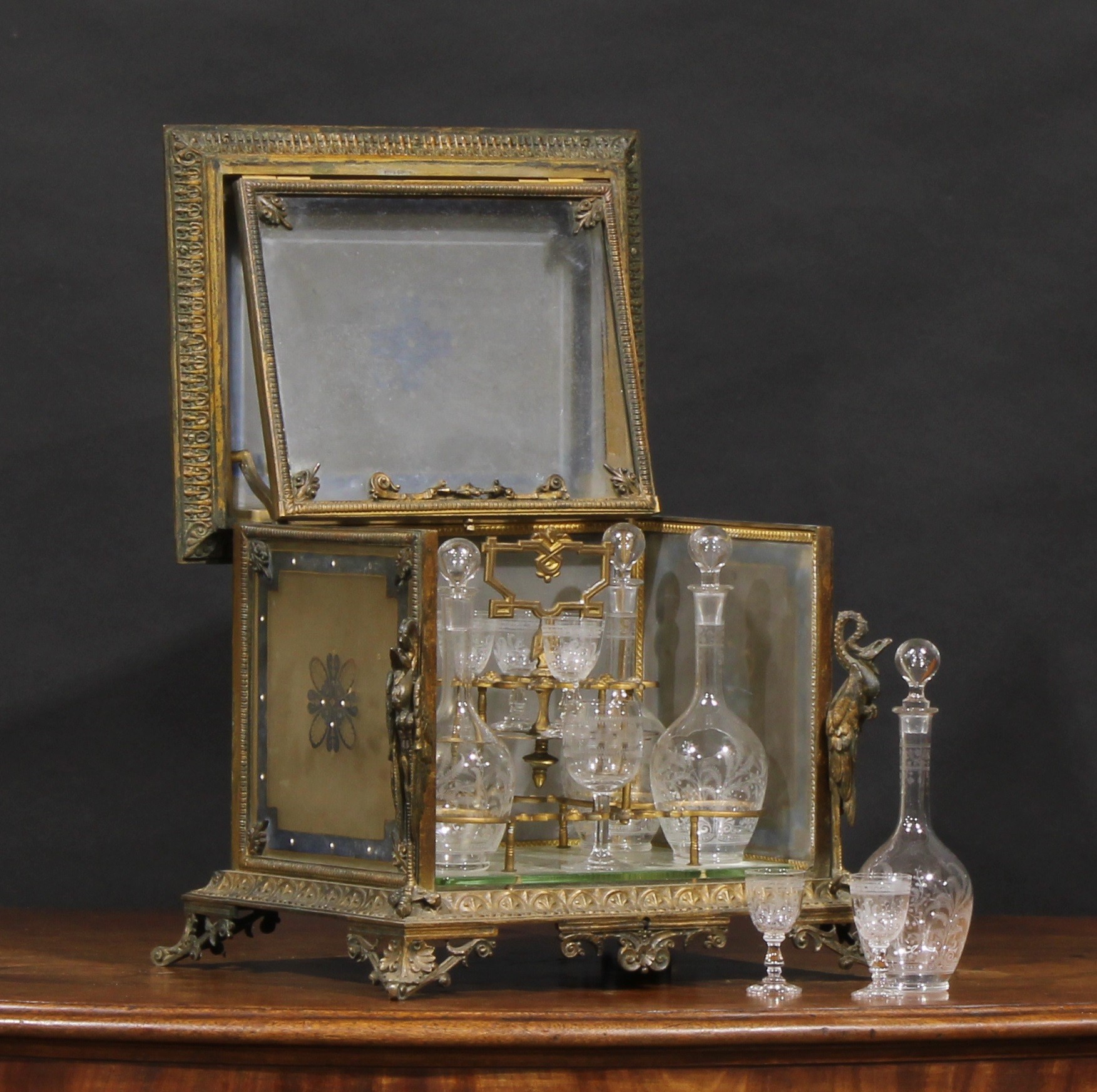 A 19th century French gilt metal and glass table top liqueur cabinet, hinged cover and folding front enclosing decanters and glasses, cast throughout in the Renaissance Revival taste, 39cm wide, c.1880