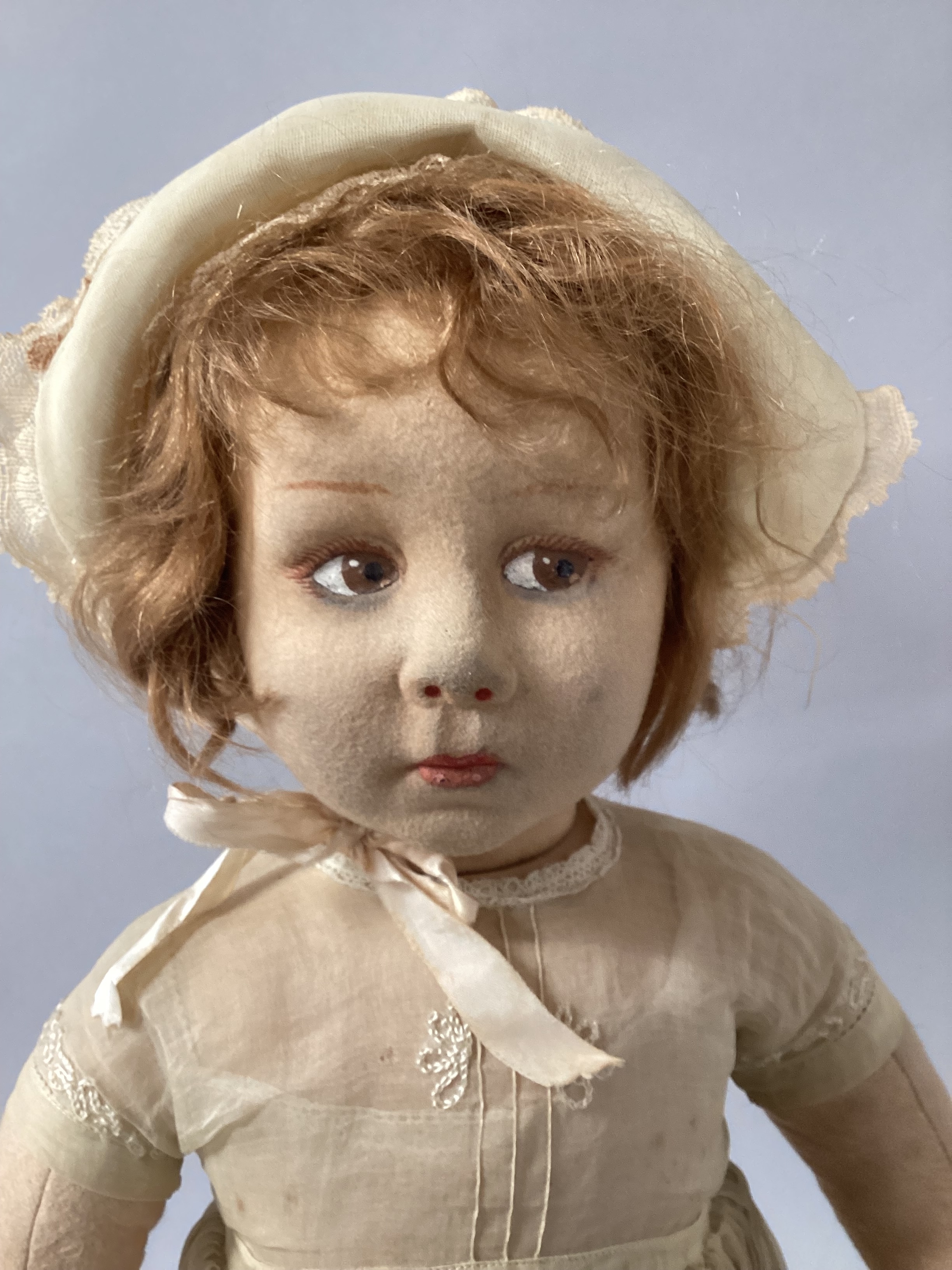 Antique Lenci Felt Large 27” doll, with black foot signature. One of the Larger series at 27” from Lenci in Turin Italy 1920s, soft hair and original primrose organdie dress and hat and onesie  and socks and later pale rose shoes, 3/4th Finger joins on both hands-surface wear to leg felt , detailed face paint and nostril highlights and vintage rose lips. An unusual large size from that series. (1)