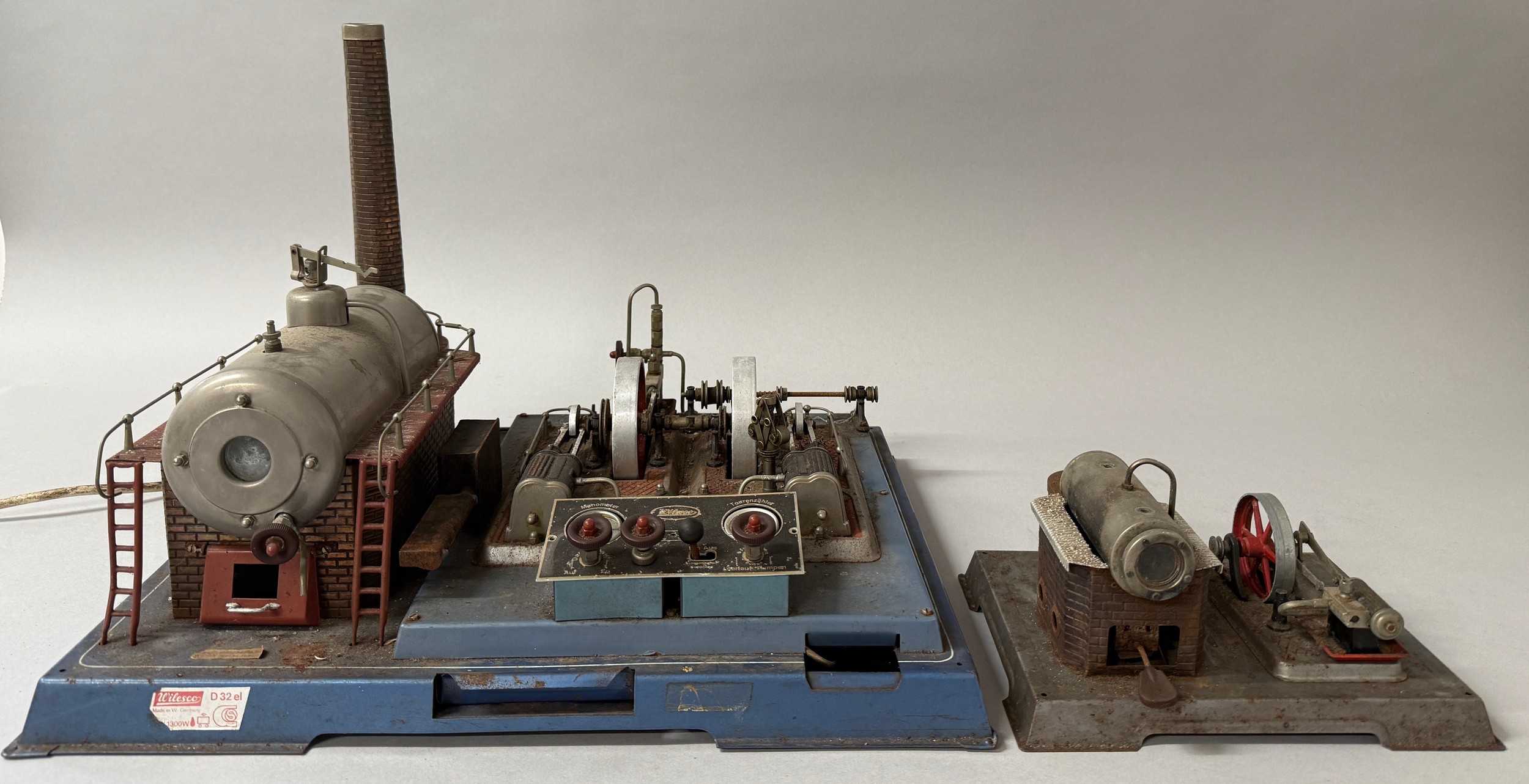 A Wileso D32el electrically heated steam engine, horizontal boiler mounted on a simulated brickwork plinth, railed gallery, chimney, pressure gauge and whistle, a pair of mill engines with generator, control panel, rectangular metal base approximately 52.5cm wide, 43cm deep, 39cm high; another similar but smaller, approximately 26 wide, 20.5 deep, 14cm high (lacking chimney) (2)