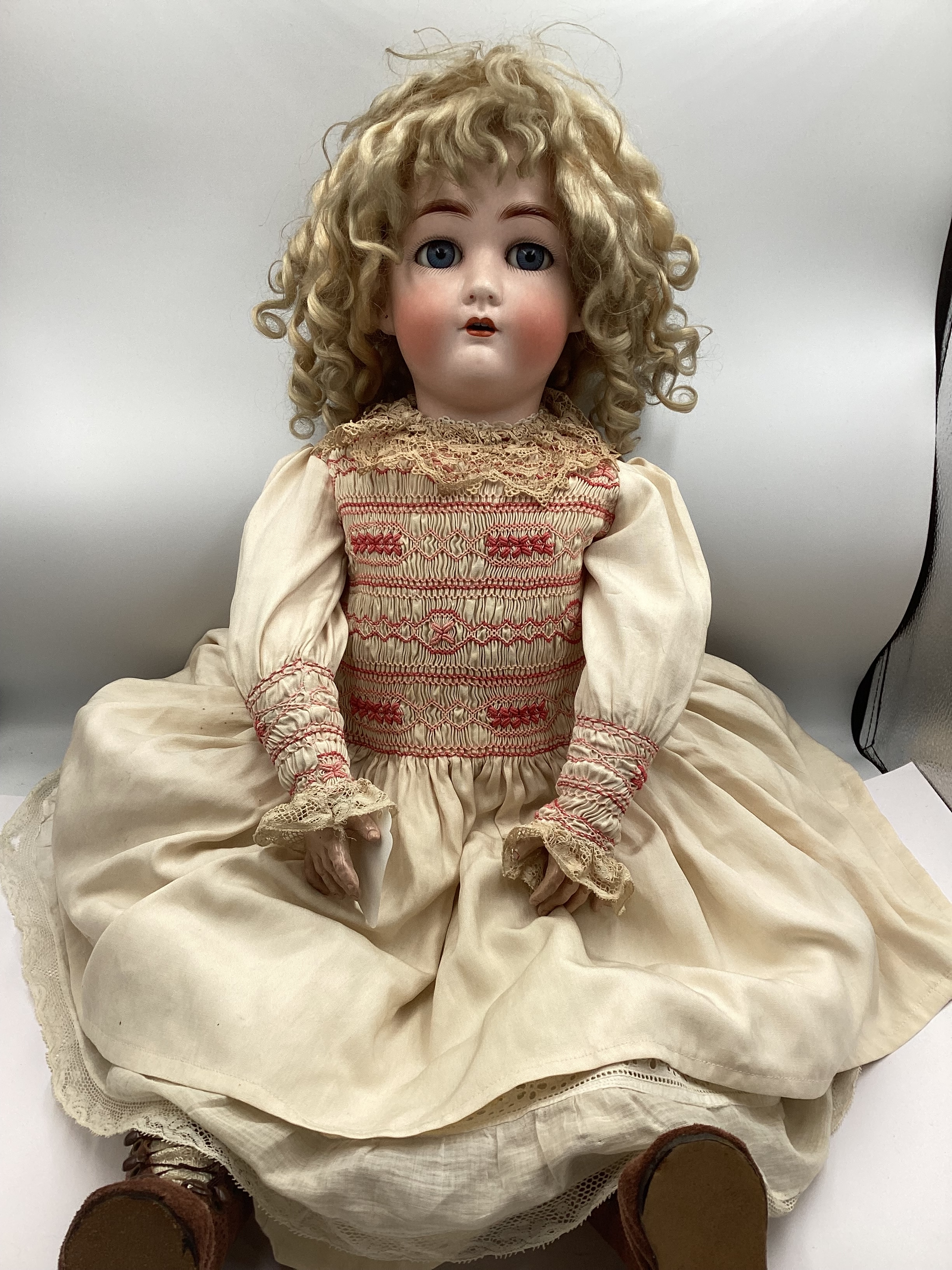 Antique Simon and Halbig Jutta Bisque head doll 1349 mould 28” firm articulation doll with fair curled wig open closed eyes , lashes sparse  good detailed hands in raspberry smocked cream dress and layers and later boots .(1)