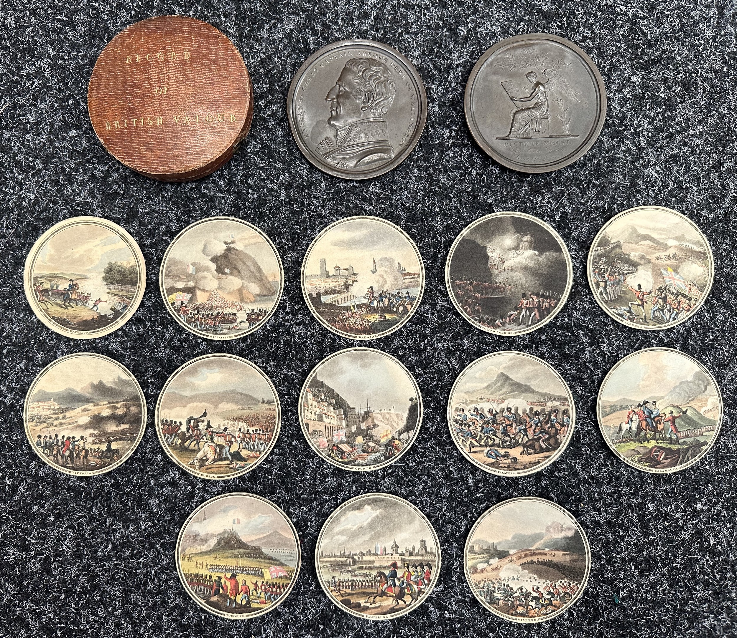 ‘Record of British Valour’, contained within a bronze circular medal box, thirteen coloured aquatints depicting the victories of the Peninsular War and Waterloo 1815, by I. Porter & E. Orme. The obverse of the medal box with relief uniformed profile bust of the Duke of Wellington bare headed signed ‘PORTER . F / Orme Direx’ [principal] under the shoulder, and encircled with the legend ‘ENGLAND'S GREAT CAPTAIN ARTHUR DUKE OF WELLINGTON’. The reverse  with the figure of Victory seated beneath a tree inscribing a tablet, ‘RECORD OF BRITISH VALOUR’ signed ‘L. Porter . F’ , and beneath / PICTURE MEDAL’  and ‘Edwd. Orme Direx’ / Bond St. London’. Complete with original leather presentation box.