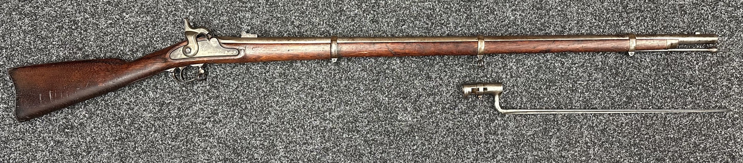 Springfiled 1863 Pattern .58 cal Percussion Cap Rifle. No serial number. Barrel length 1000mm. Barrel is marked "IS 1863". Overall length 142cm. Lock marked with US Eagle and 1863 and US Springfield. Two position flip up sight. Working action which holds at both full and half cock. Barrel bands are all marked "U". Comes complete with Ramrod and correct Bayonet which is 45cm in length. No markings. NOTE: Section 58(2) No licence required in the UK.