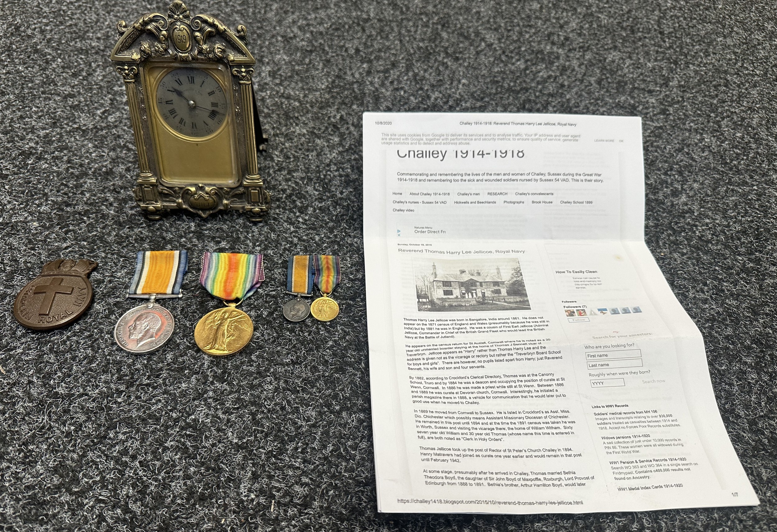 WW1 British Royal Navy Chaplain Medal Group comprising of War Medal and Victory Medal to Chaplain Thomas Harry Lee Jellicoe, RN. Along with a matching pair of miniature medals, very rare Royal Navy Chaplains Officers Bronze Cap Badge and a small brass mantle clock engraved to the reverse "Presented to The Reverend THL Jellicoe, Rector of Chailey by some of his friends as a token of affection on his return from Active Service. Front of the clock has date 1919 and his initials. Clock runs and ticks, no key. Along with three pages of research about his life. He was a cousin of John Jellicoe, 1st Earl Jellicoe of Battle of Jutland fame.