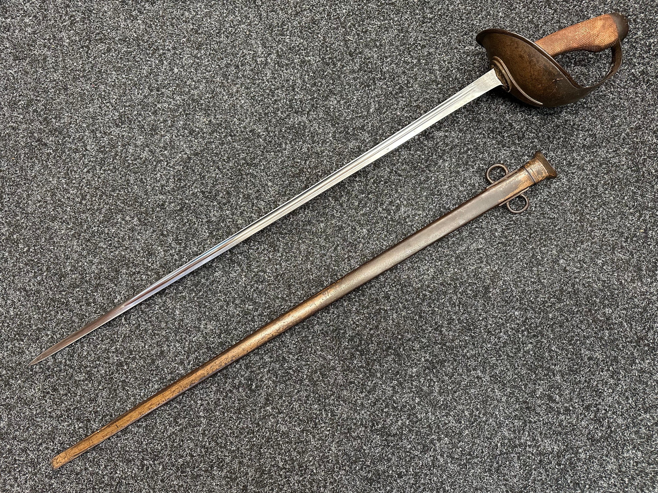 WW1 British 1908 Pattern Cavalry Sword with fullered single edged blade maker marked and dated "Enfield 6-15" 890mm in length. Leather washer to blade. Guard is marked "808". Wooden grips. Overall length 110cm. Complete with scabbard, again maker marked Enfield, which is unit marked "RCR 808". Traces of original paint to the scabbard.