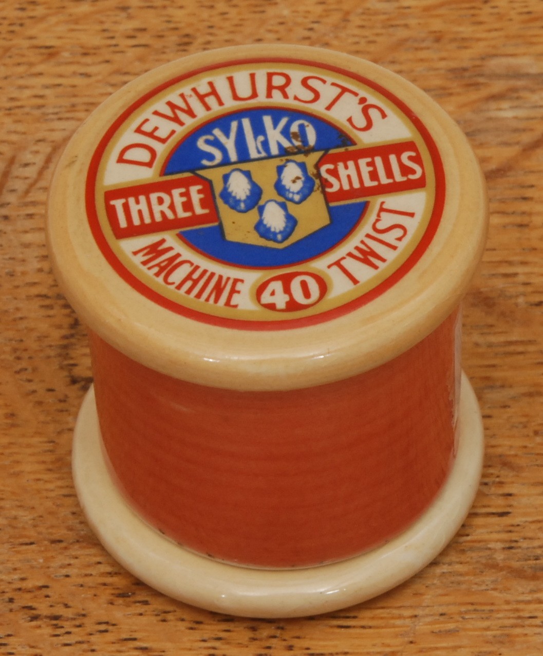 Advertising - a Dewhurst's Sylko Three Shells ceramic vesta/needle case, "Machine Twist 40", with salmon pink effect cotton, 5cm