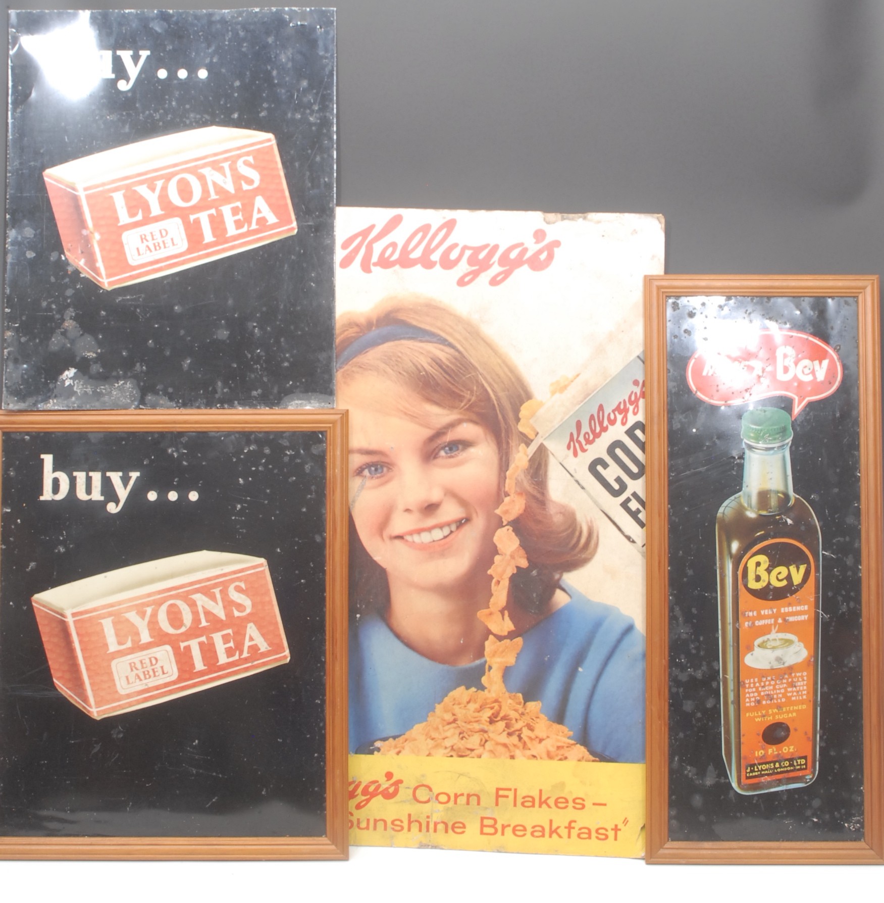 Advertising - a mid 20th century rectangular pictorial tin sign, 'HAVE A - Bev', illustrated in polychrome with a bottle of Bev Essence of Coffee & Chicory, later framed, 66.5cm x 27cm overall; a mid 20th century rectangular pictorial tin sign, 'buy... LYONS RED LABEL TEA', illustrated in polychrome with a packet of Lyons Tea, later framed, 51cm x 42cm; another, unframed; a pictorial showcard, 'Kellogg's Corn Flakes', 74.5cm x 49.5cm (4)