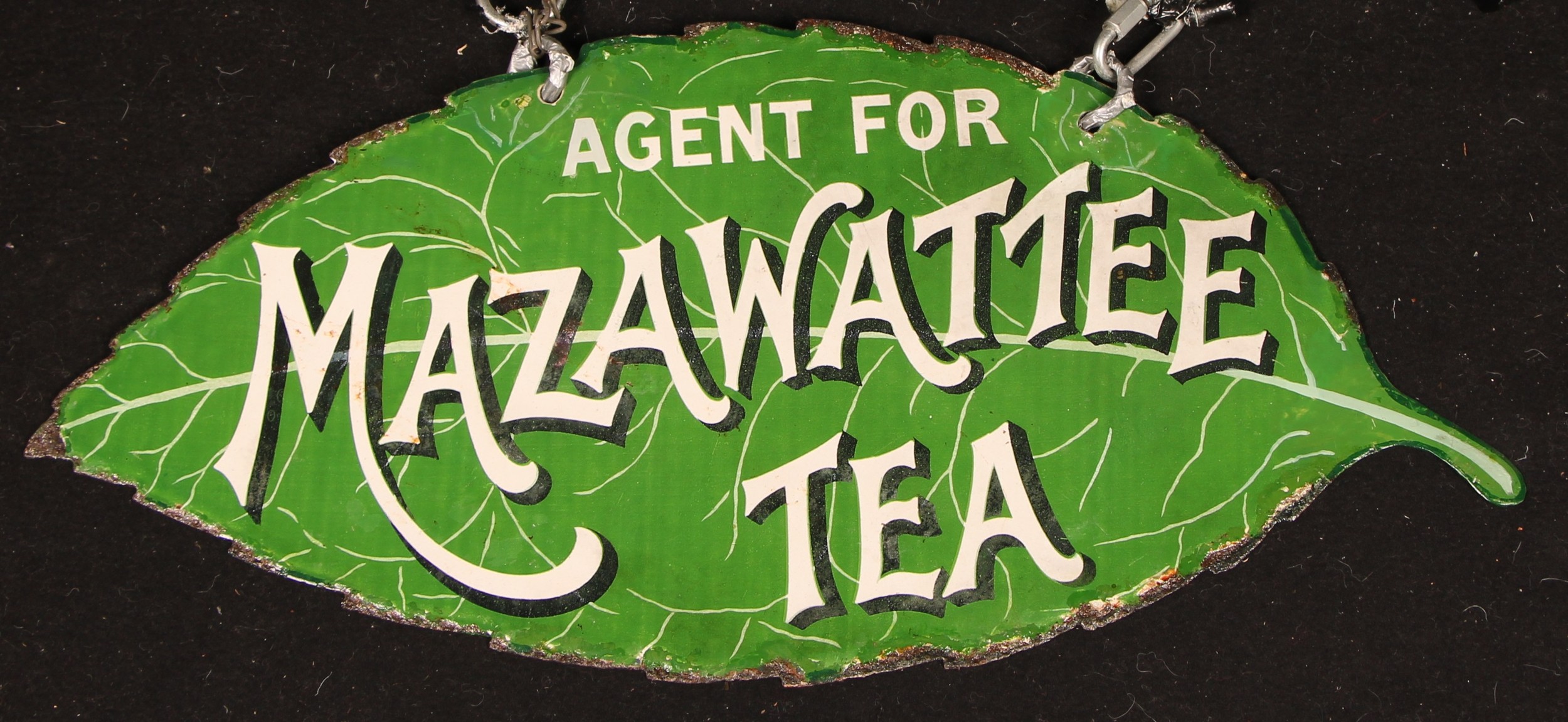 Advertising - an early 20th century shaped double sided enamel sign, Agents For Mazawattee Tea, in the form of a tea leaf, inscribed in white on a green ground, with suspension holes, later wall bracket, 25.5cm high x 48cm wide