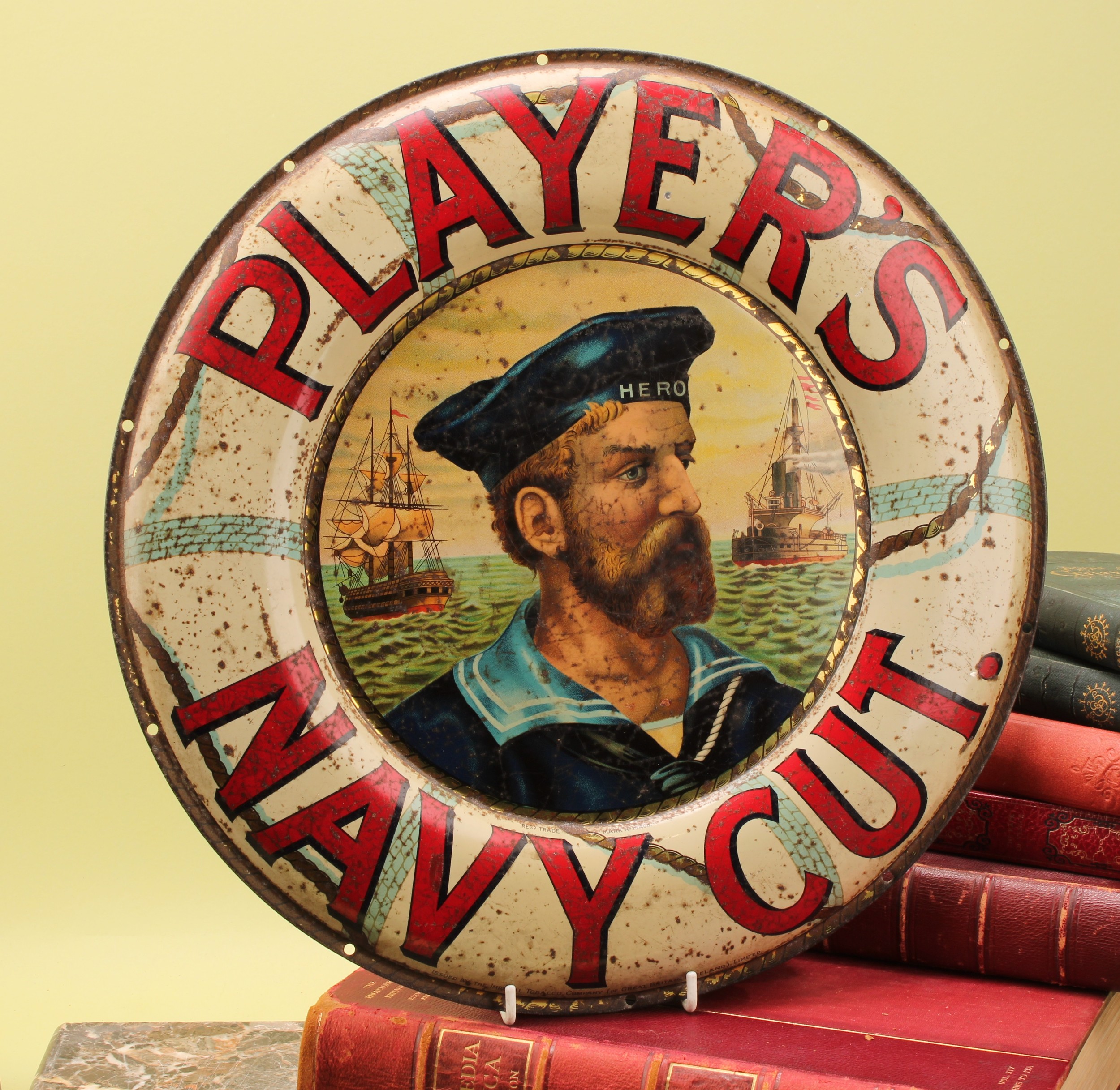 Advertising - Tobacco - a circular pictorial pressed tin sign, Player's Navy Cut, inscribed in red on life ring border, the field illustrated with the 'Hero' sailor, 39cm diameter
