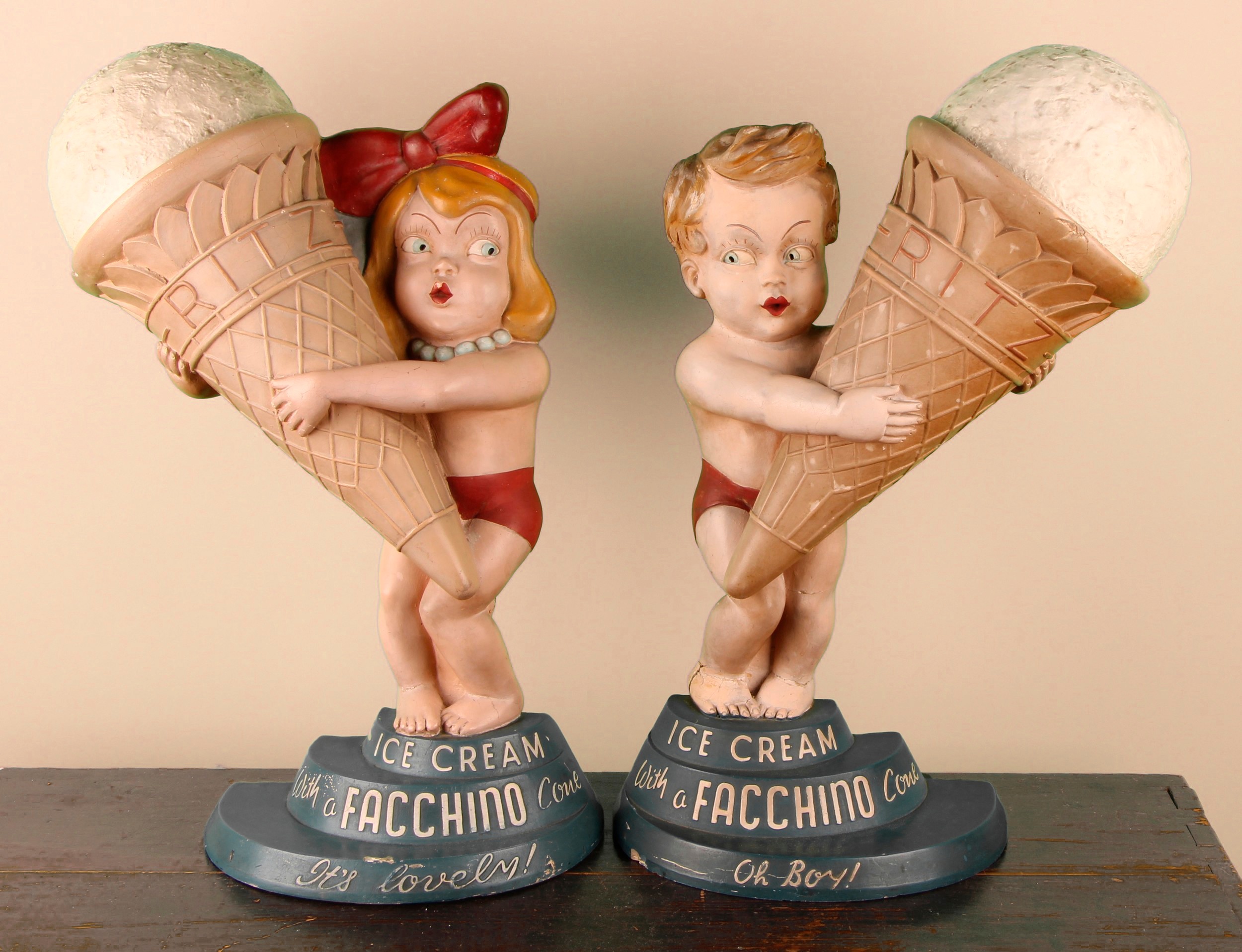 Advertising - a pair of mid 20th century composite shop display figures, Facchino Ice Cream, modelled as a boy and girl holding an oversized ice cream, each embossed and inscribed 'Ice Cream with a Facchino Cone', the boy 'Oh Boy!', the girl 'It's Lovely!', in polychrome, 55.5cm high