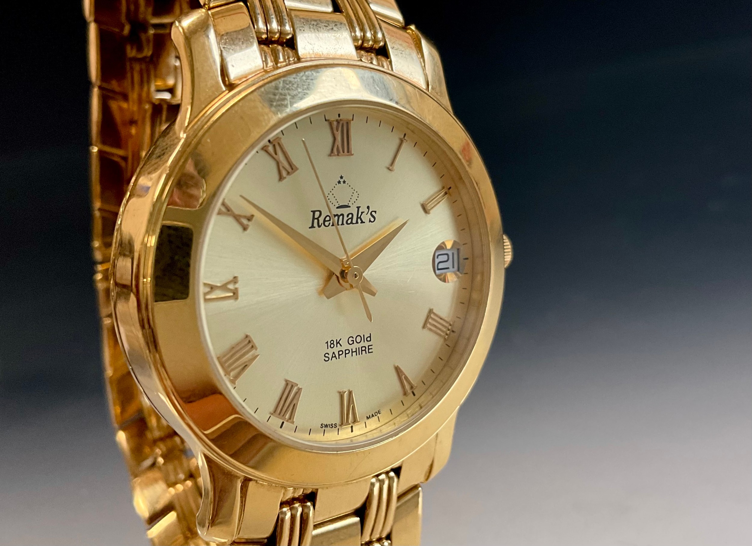 An 18ct gold cased automatic Swiss dress wristwatch, ref 7359, gold colour dial signed Remak's, raised Roman numerals, centre seconds date aperture, 32mm diameter case, sapphire crystal, case back marked 18 CARAT SOLID GOLD, WATER RESISTANT, SCRATCHPROOF SAPPHIRE CRYSTAL, AUTOMATIC, SWISS MADE, 750 -18K GOLD, with fancy link 18ct gold strap, deployment clasp, with spare strap links, 83.1g gross;  boxed with purchase warranty card from Popley Kewalram Jewellers, Dubai, dated 03/02/01